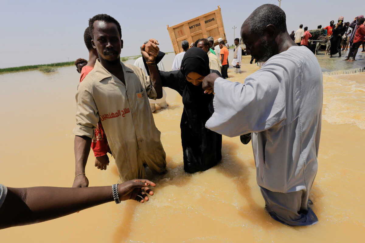 People cross the water during a flood in Al-Managil locality, Sudan, August 23, 2022. REUTERS