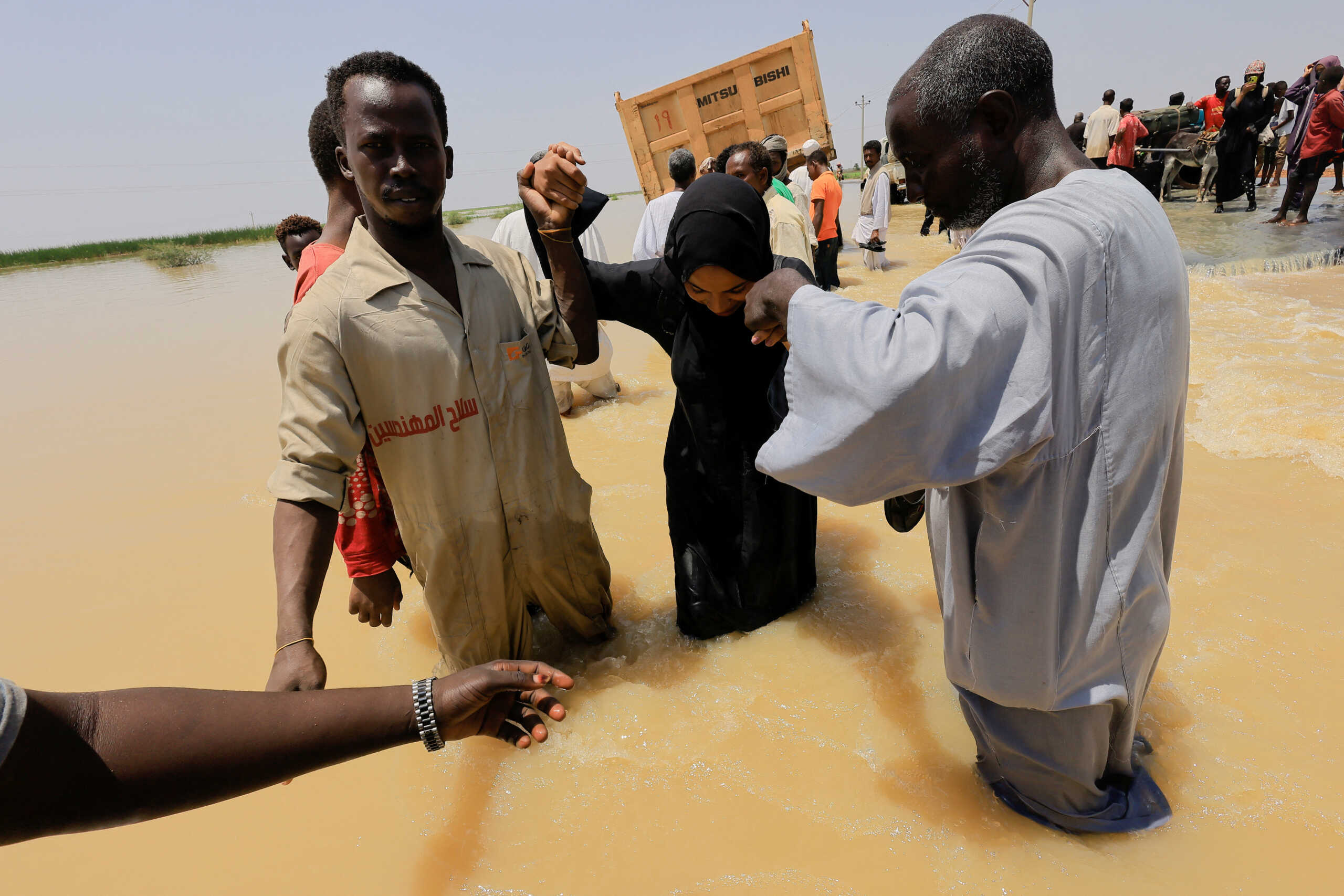 People cross the water during a flood in Al-Managil locality, Sudan, August 23, 2022. REUTERS