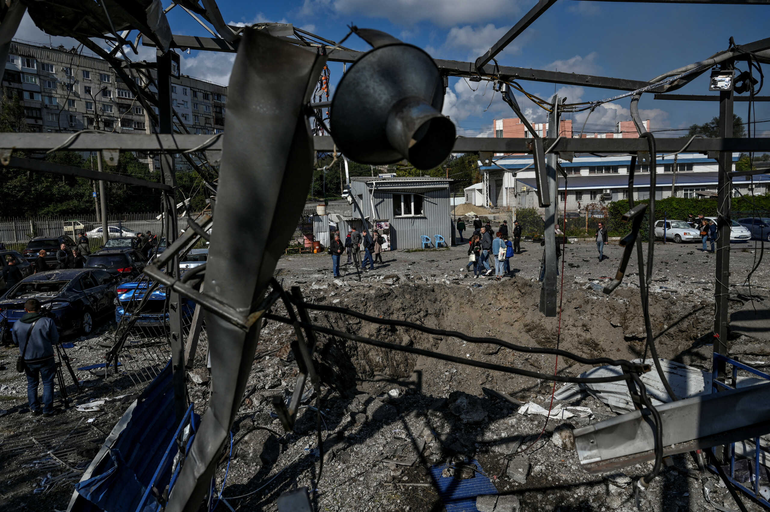 People stand next to a crater left by a Russian missile strike, amis Russia's attack on Ukraine, in Zaporizhzhia, Ukraine September 23, 2022. REUTERS