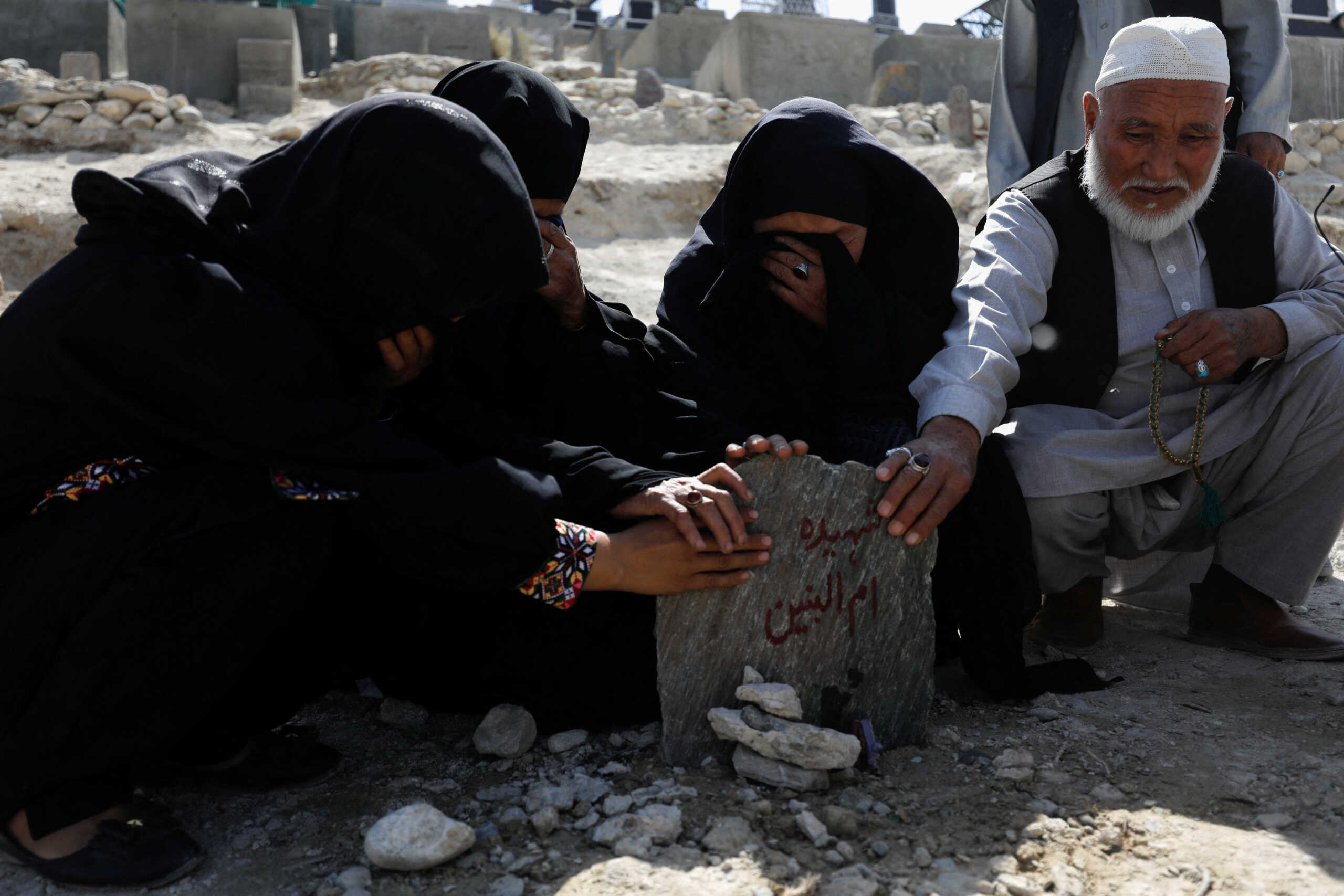 The family members of Um al-Banin, who was killed in a suicide attack in a tutoring center in Dasht-e-Barchi district in the west of Kabul, pray at her grave in Kabul, Afghanistan, October 2, 2022. REUTERS