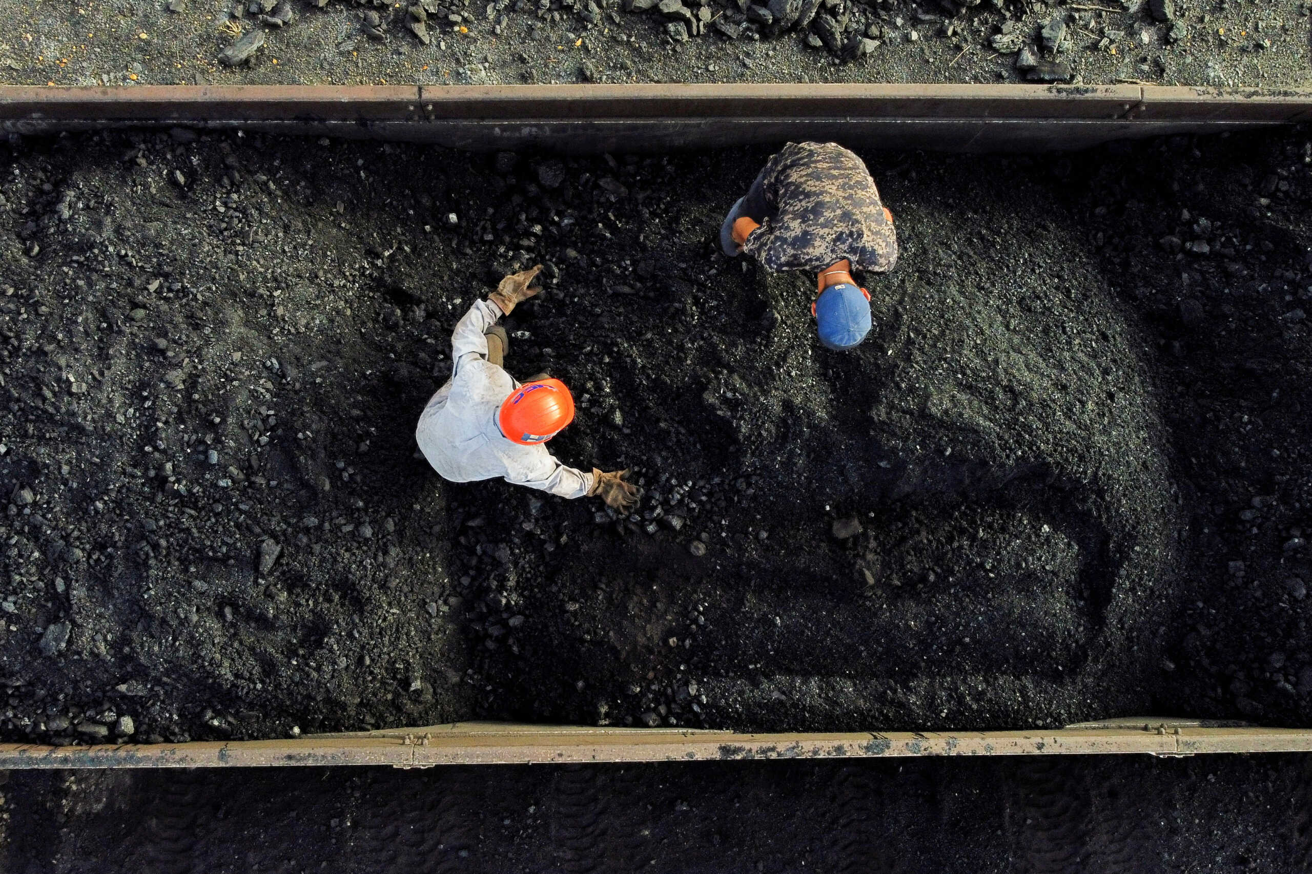 Miners Luis Felipe Martinez, 47, and Eduardo Isai Flores Maldonado, 18, separate stones from coal before it is transported to be sold, at a coal mine, in Sabinas, Mexico August 20, 2022. On August 3, 10 miners were trapped in the nearby coal mine of El Pinabete as water broke through a shaft wall and flooded the tunnels the men were working in. Nearly two months later, their bodies have still not been recovered.   REUTERS