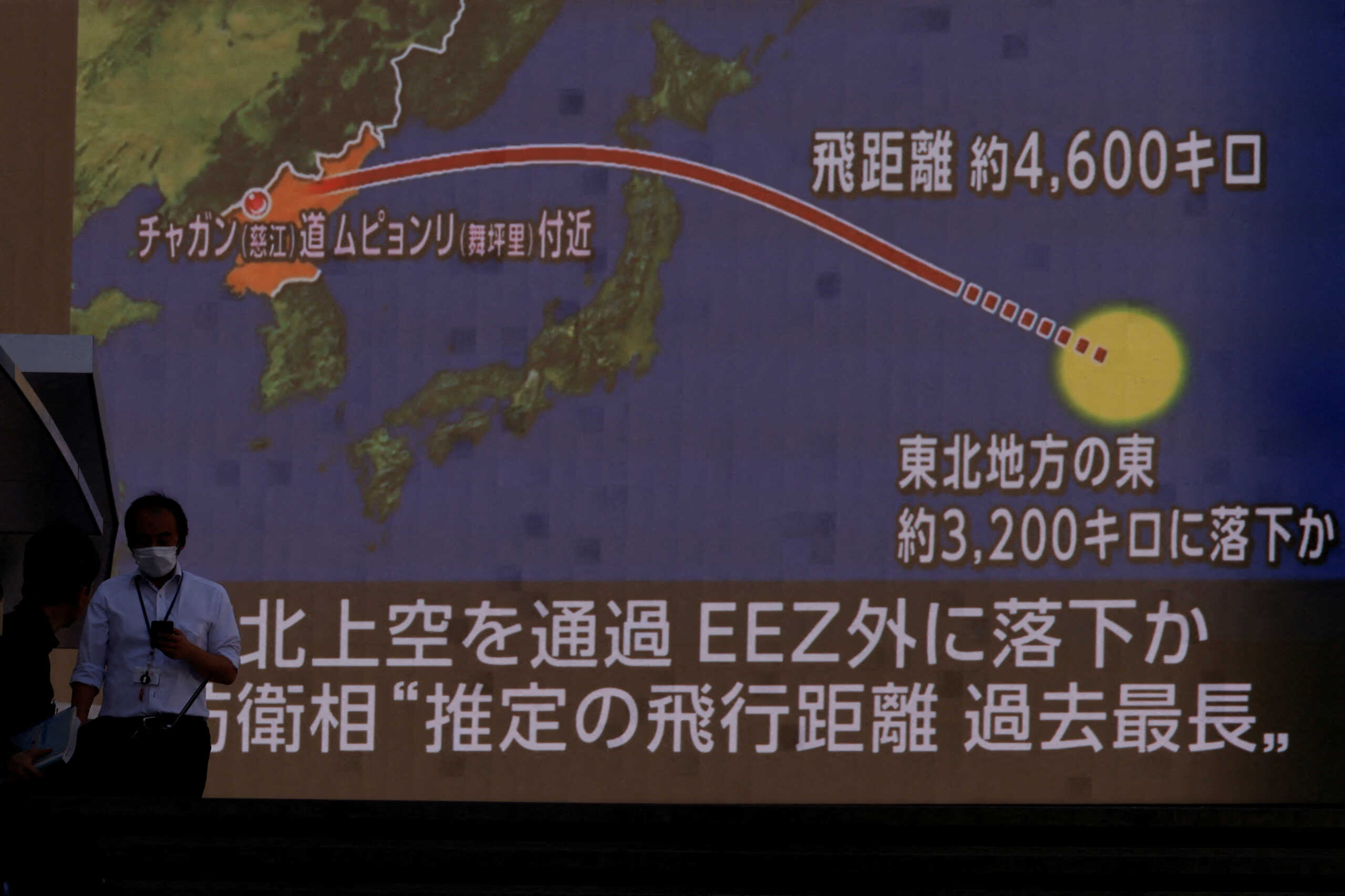 FILE PHOTO: People walk in front of a screen showing a news report about North Korea firing a ballistic missile over Japan, in Tokyo, Japan October 4, 2022. REUTERS