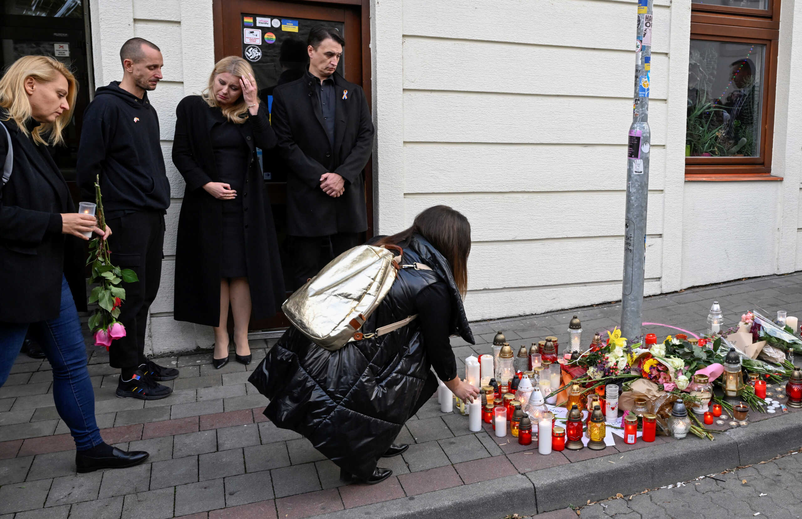 Slovakia's President Zuzana Caputova stands next to her partner Juraj Rizman and the owner of a gay bar as a person lays a tribute at the site of a shooting in Bratislava, Slovakia October 13, 2022. REUTERS