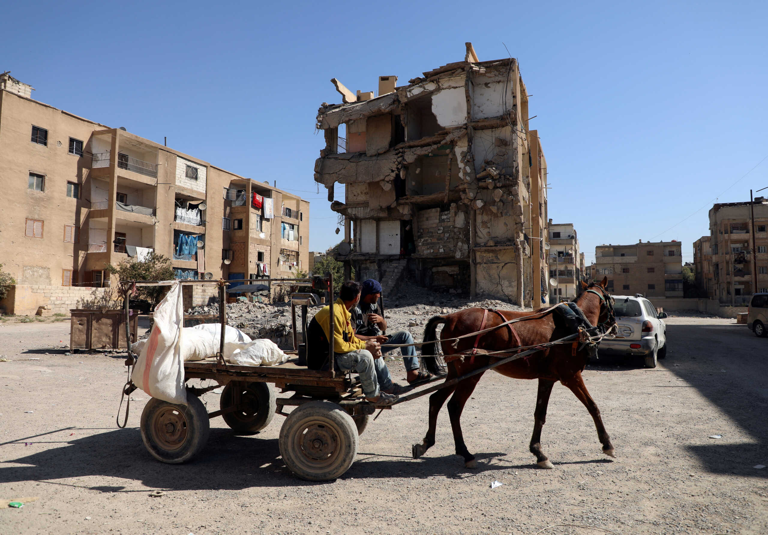Men ride a horse cart past a damaged a building in Raqqa, Syria October 12, 2022. REUTERS
