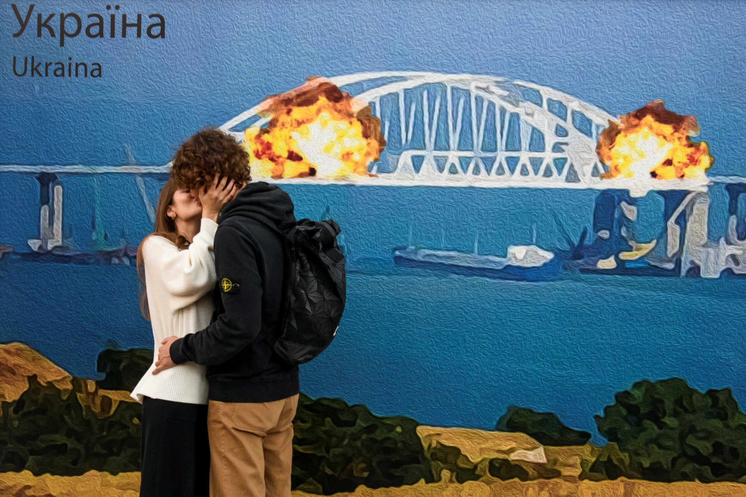 A couple kisses in front of an artwork depicting Kerch bridge on fire, amid Russia's attack on Ukraine, in central Kyiv, Ukraine October 8, 2022.  REUTERS