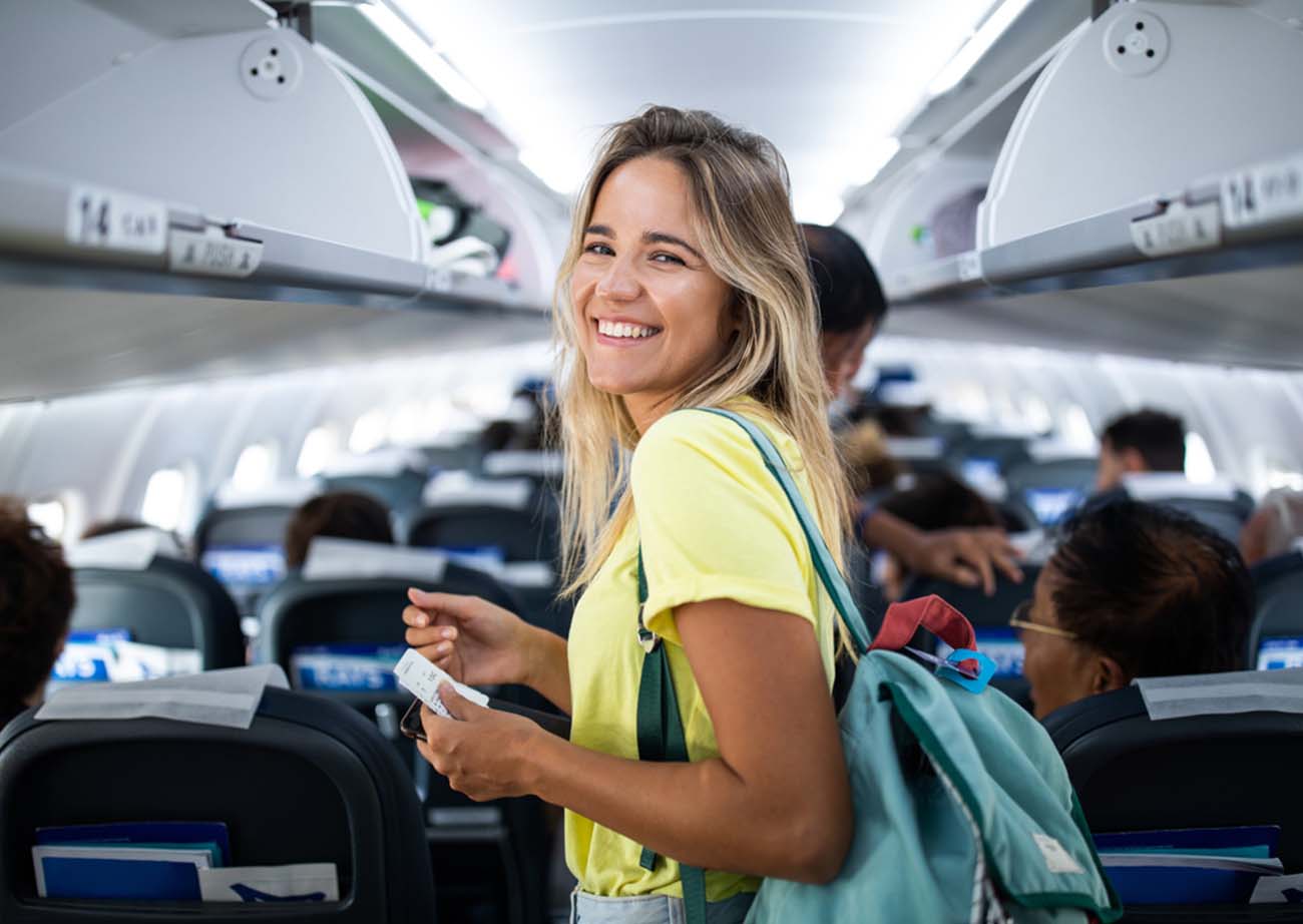 Happy woman boarding the airplane and looking at camera.