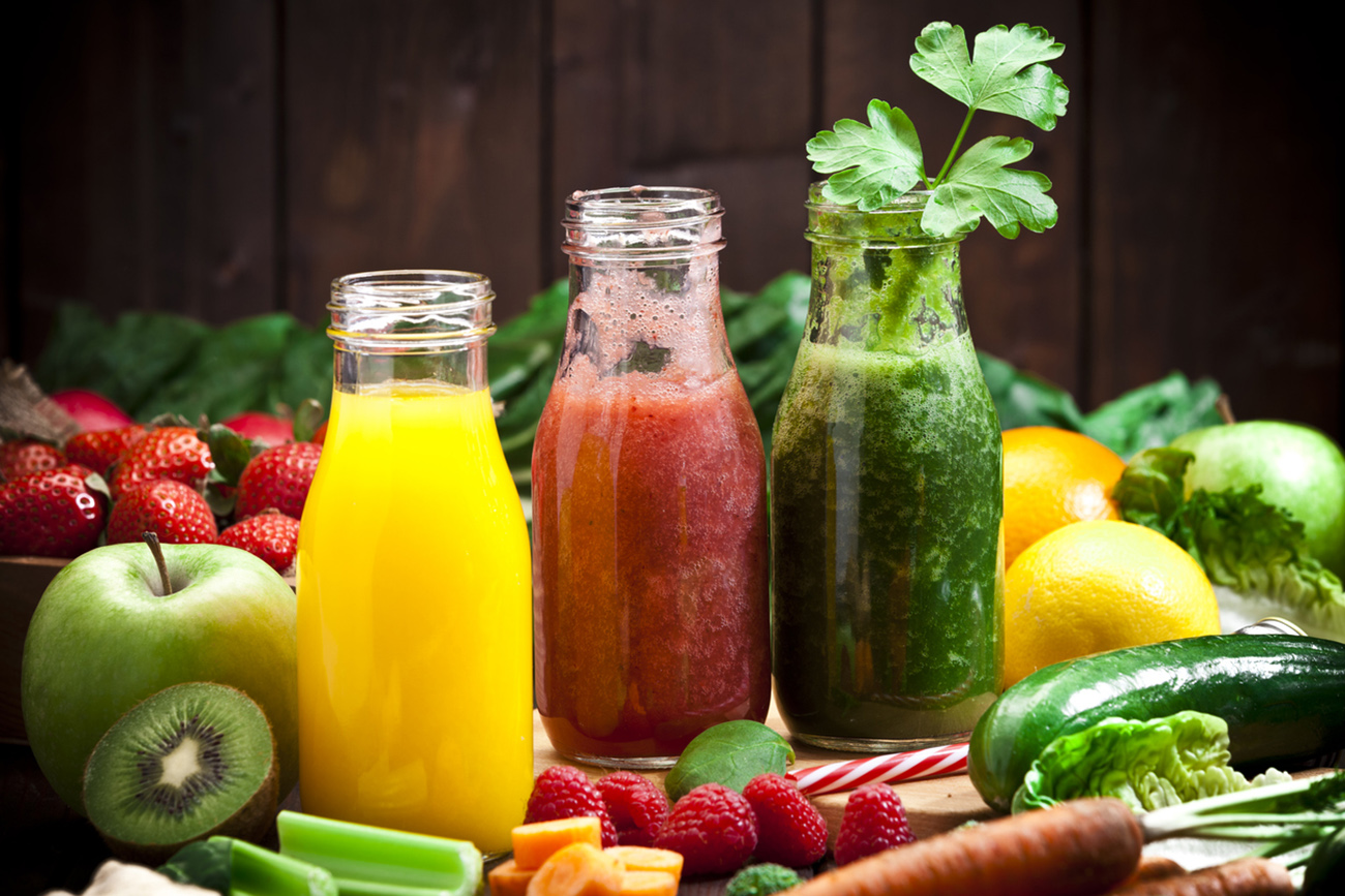 Healthy eating concept: Horizontal shot of three detox drinks in glass bottles with fruits and vegetables all around them on rustic wood table. DSRL studio photo taken with Canon EOS 5D Mk II and Canon EF 70-200mm f