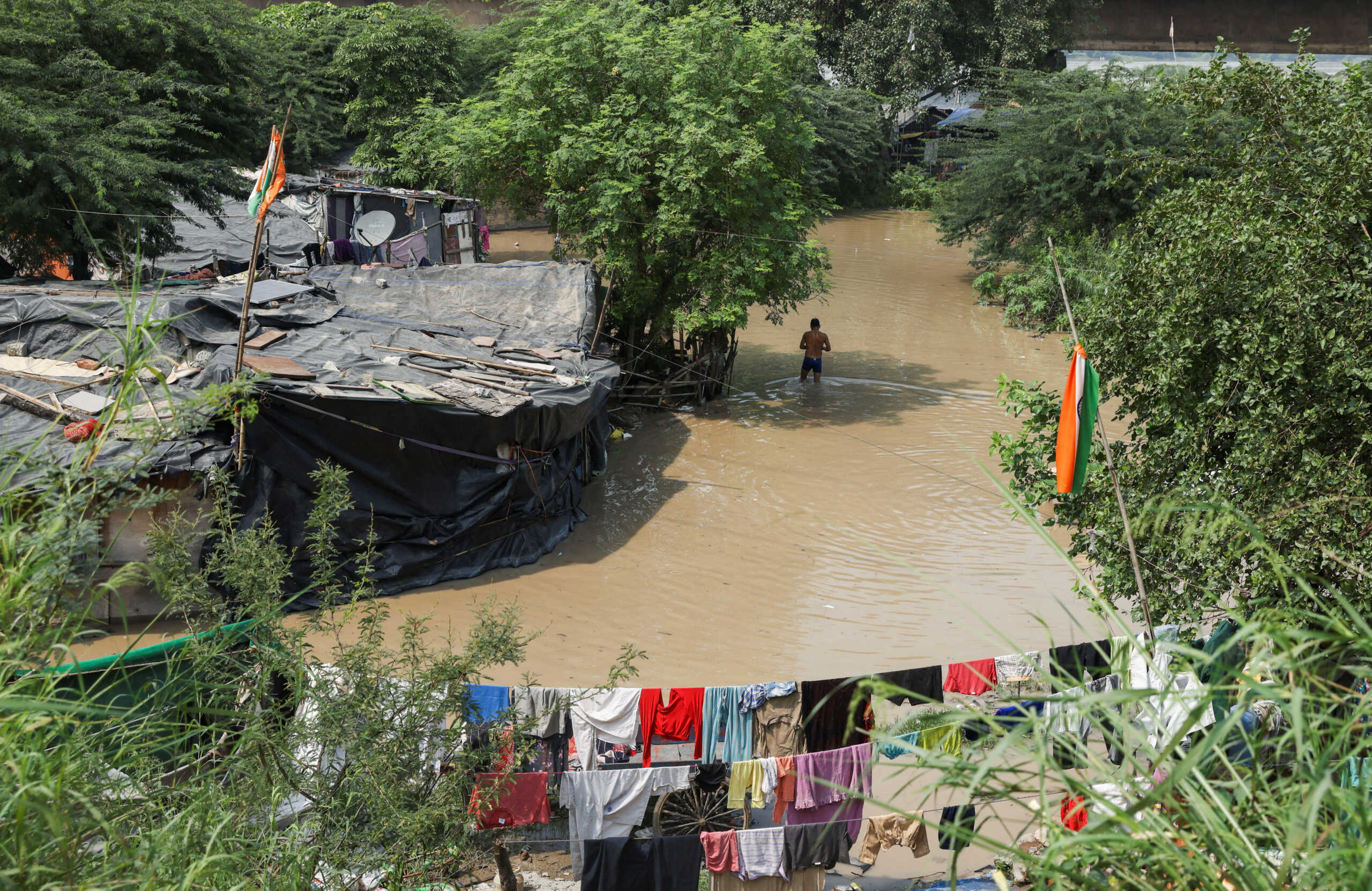 A person wades through a flooded area of a slum on the banks of Yamuna River in New Delhi, India, September 28, 2022. REUTERS