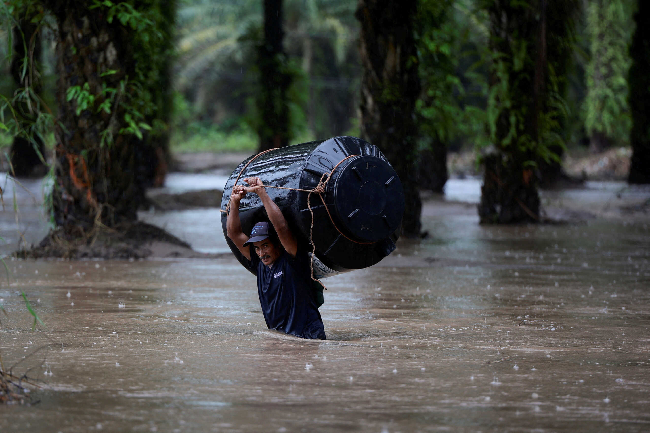 A man carries an empty water tank through a flooded area after the impact of the tropical storm Julia, in Progreso, Honduras October 9, 2022. REUTERS