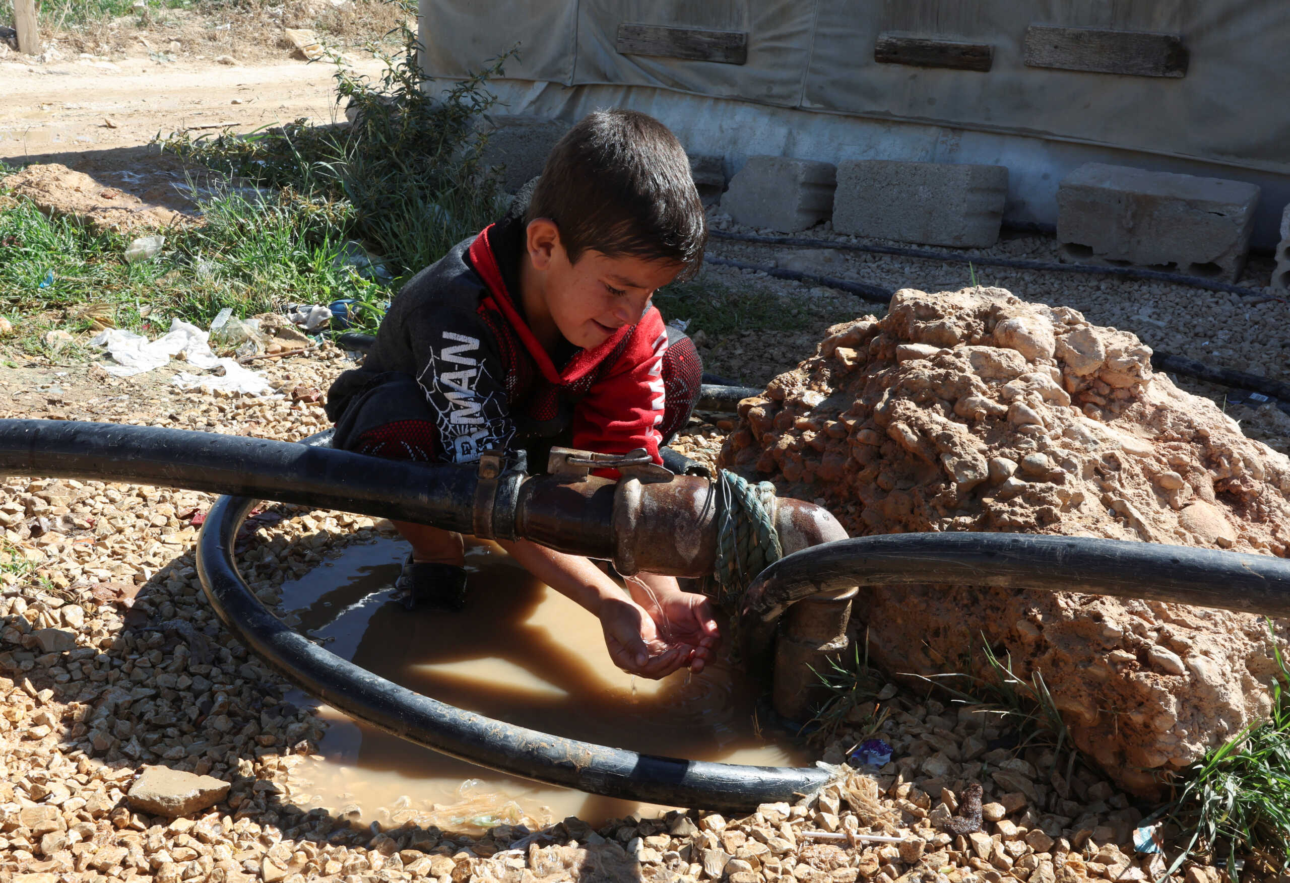 A Syrian refugee boy washes himself at an informal camp in Qab Elias, in Lebanon's Bekaa Valley October 18, 2022. REUTERS