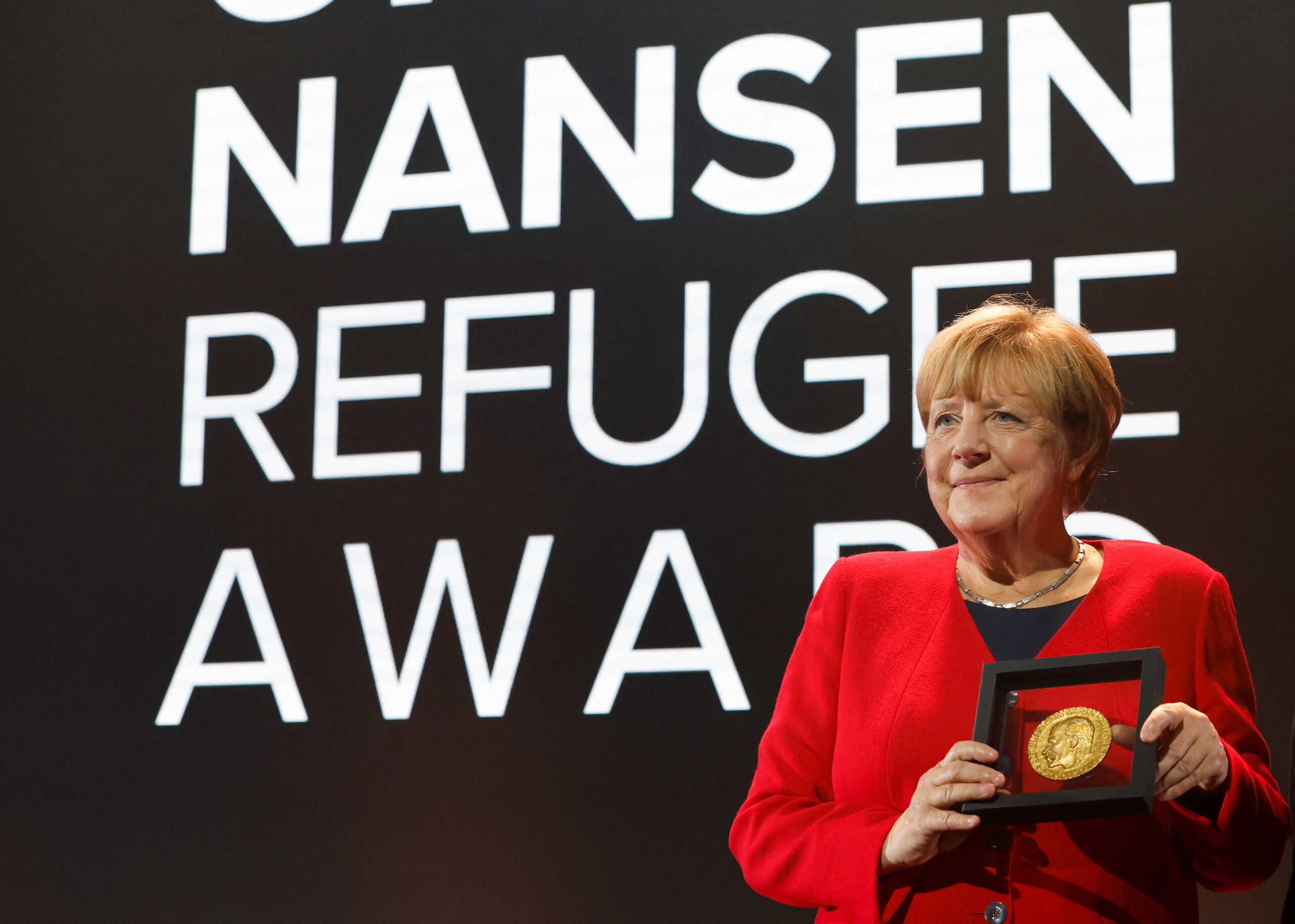 Angela Merkel poses with the UNHCR Nansen Refugee Award for protecting refugees at height of Syria crisis, during a ceremony in Geneva, Switzerland, October 10, 2022. REUTERS
