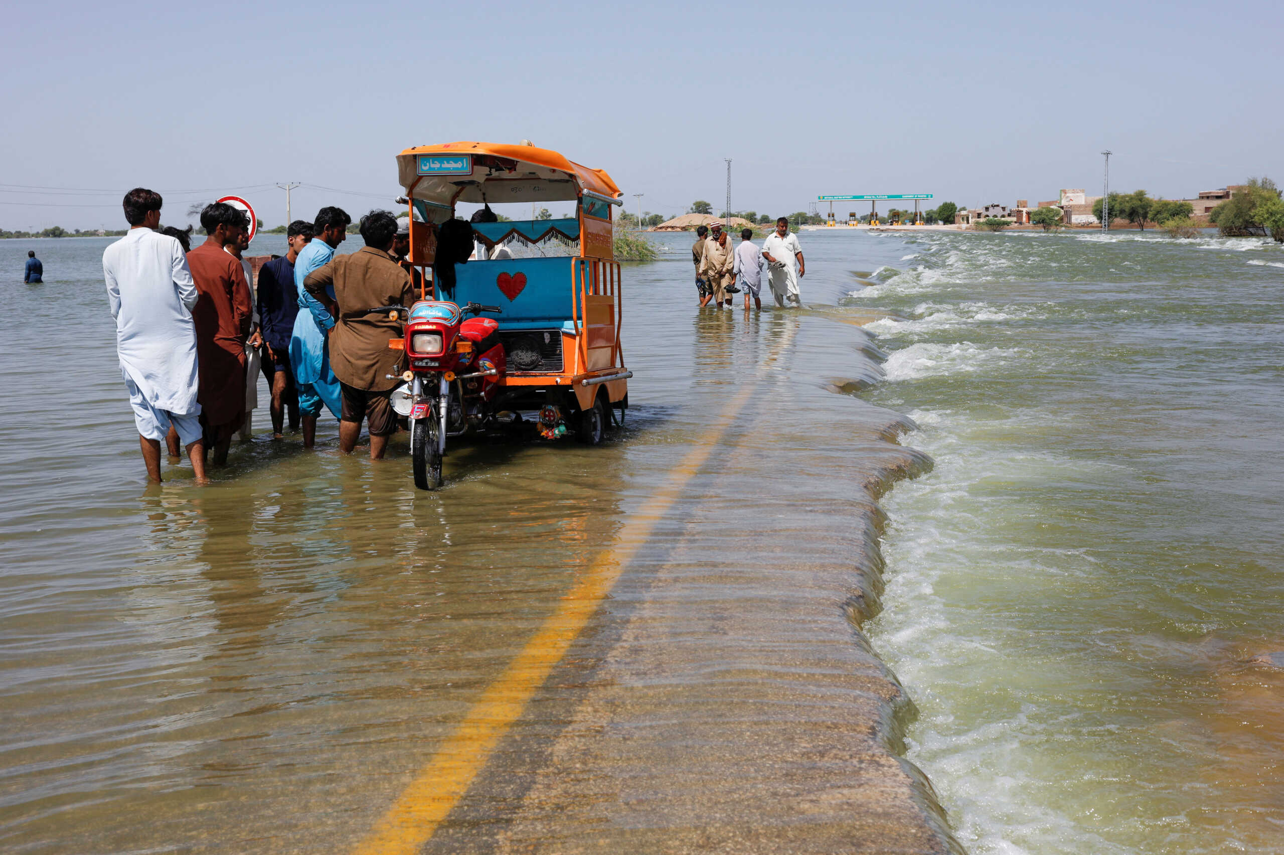 Displaced people stand on flooded highway, following rains and floods during the monsoon season in Sehwan, Pakistan, September 16, 2022. REUTERS