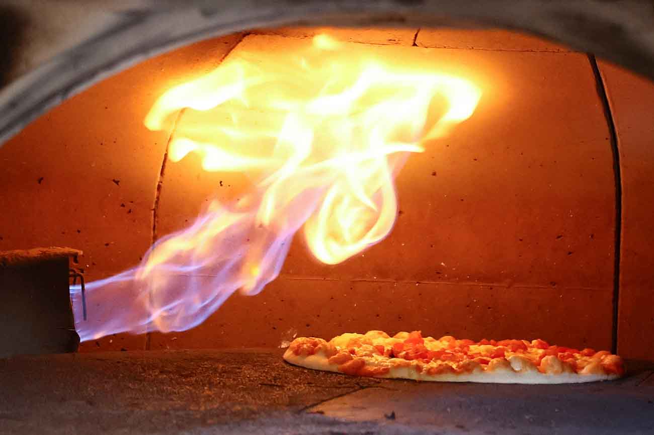 FILE PHOTO: A pizza is baked in a traditional Italian pizza oven fired with natural gas, at a restaurant in Bonn, Germany, October 11, 2022. REUTERS