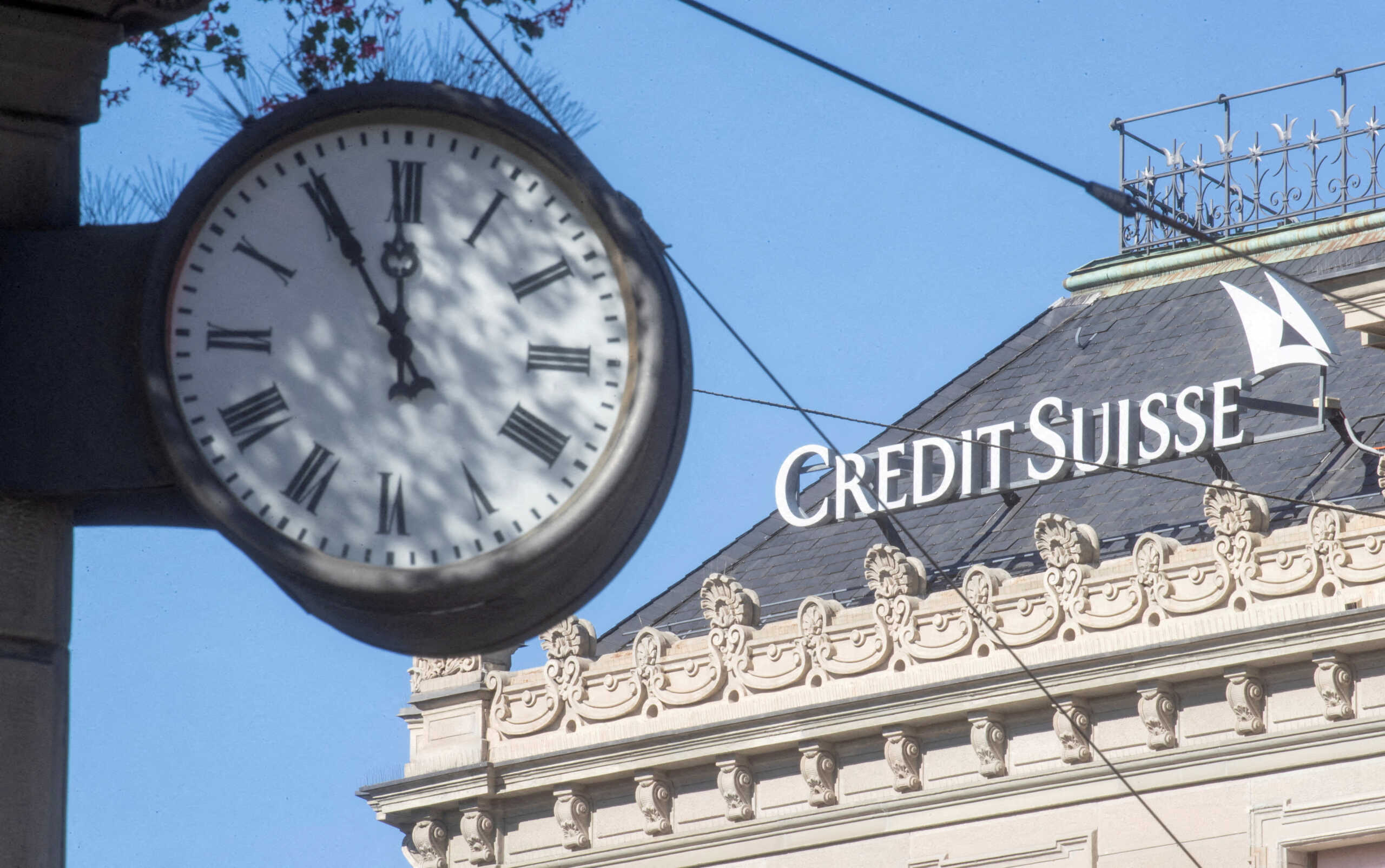 FILE PHOTO: A clock is seen near the logo of Swiss bank Credit Suisse at the Paradeplatz square in Zurich, Switzerland October 5, 2022. REUTERS