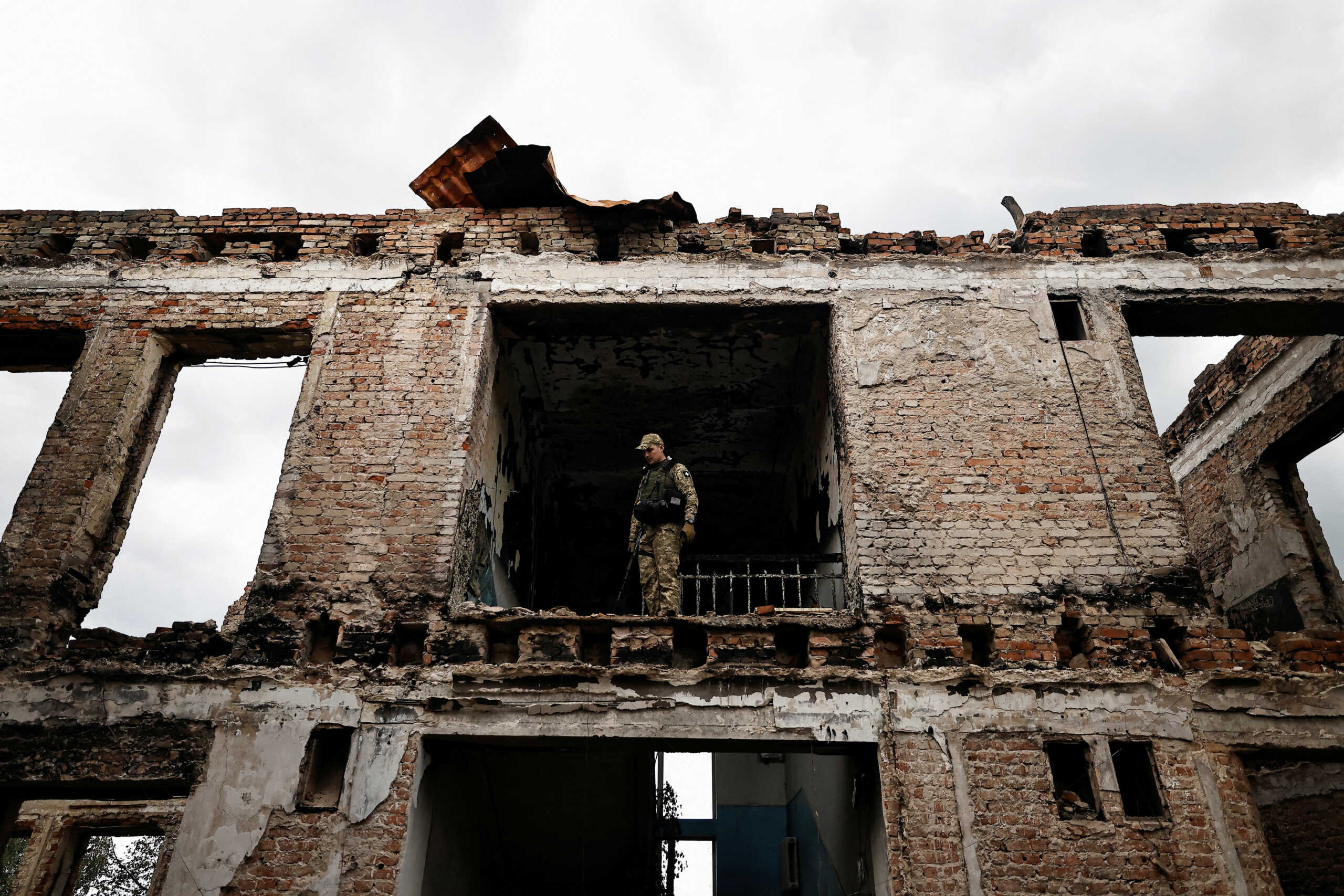 Illia Yerlash, a Ukrainian army officer, stands among the remains of a school that was destroyed during the fighting between Russian troops and the Ukrainian army, amid Russia's invasion of Ukraine, in the recently liberated town of Lyman, Donetsk region, Ukraine, October 5, 2022. REUTERS