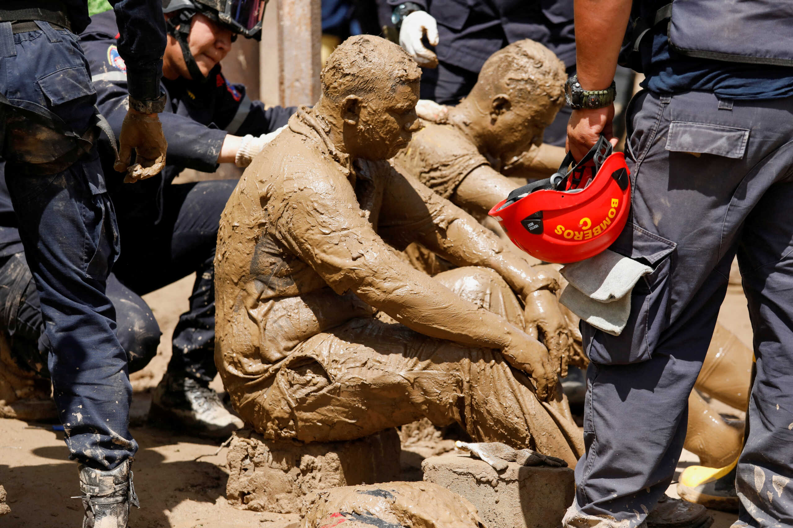 Volunteer rescuers who were attacked by wasps while removing debris to recover the body of a person are attended by firefighters, as the search of missing persons who were swept away on Saturday by devastating floods following heavy rain continues, in Las Tejerias, Aragua state, Venezuela October 10, 2022. REUTERS