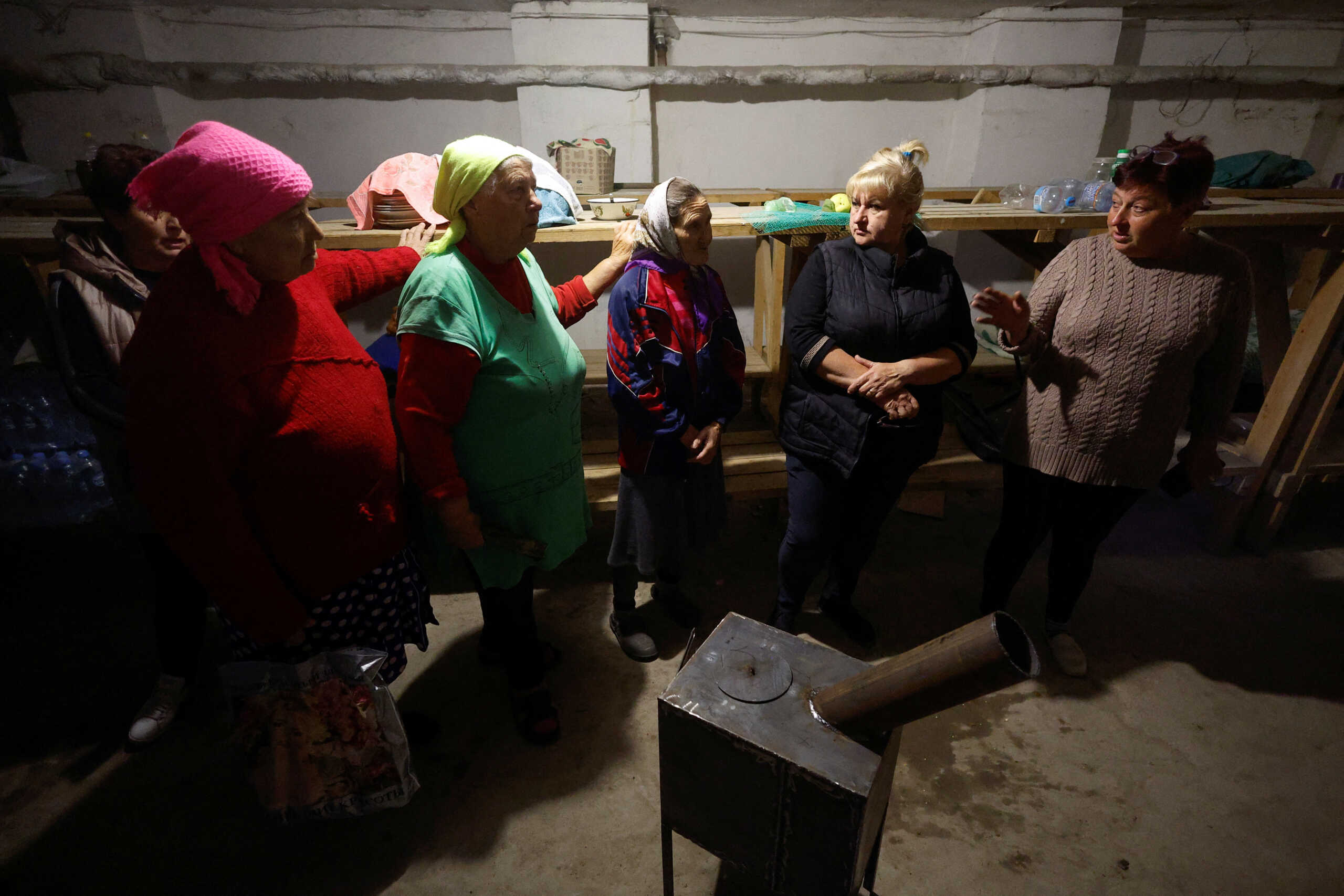 Local women gather in a bomb shelter around a wood stove delivered by volunteers, amid Russia's attack on Ukraine, in the village of Lupareve near a frontline in Mykolaiv region, Ukraine October 18, 2022.  REUTERS