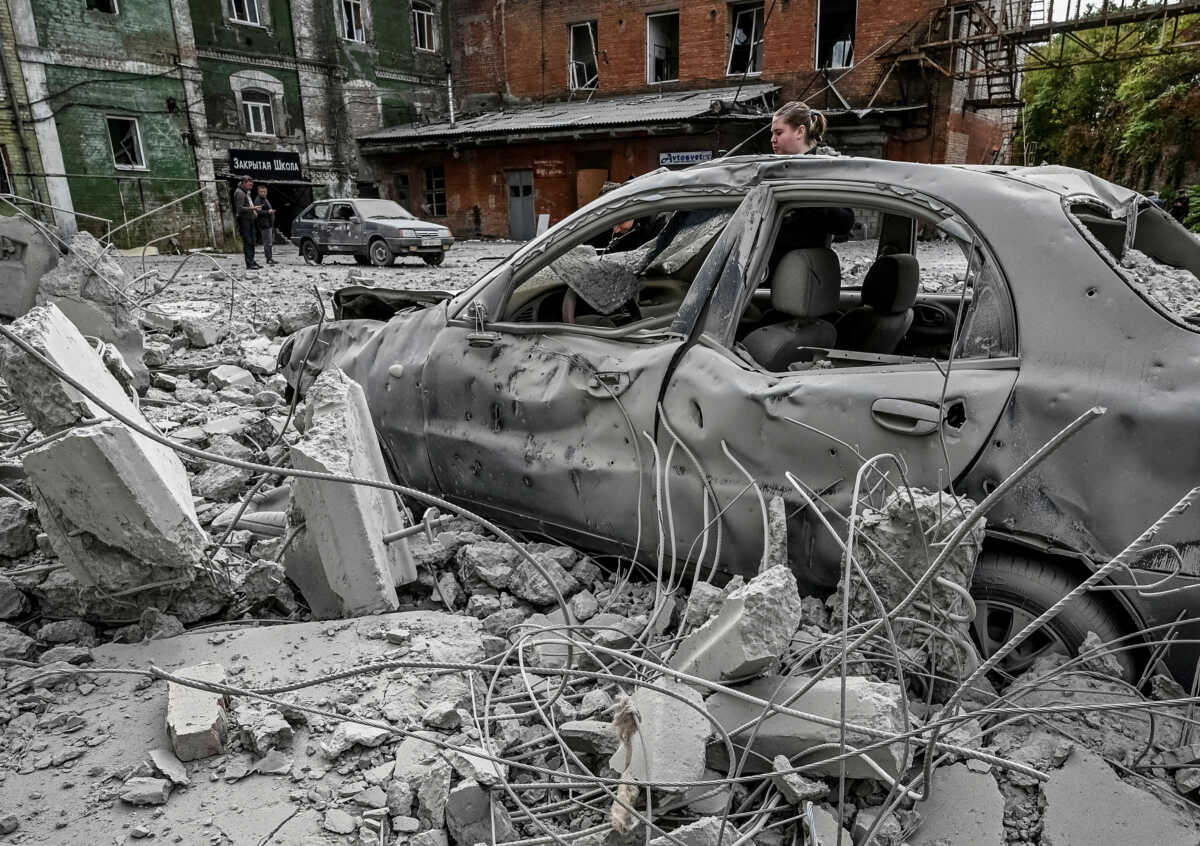 A woman stands near her destroyed car near an old mill, built around 1885, also destroyed during a Russian missile attack in Zaporizhzhia, Ukraine October 14, 2022. REUTERS