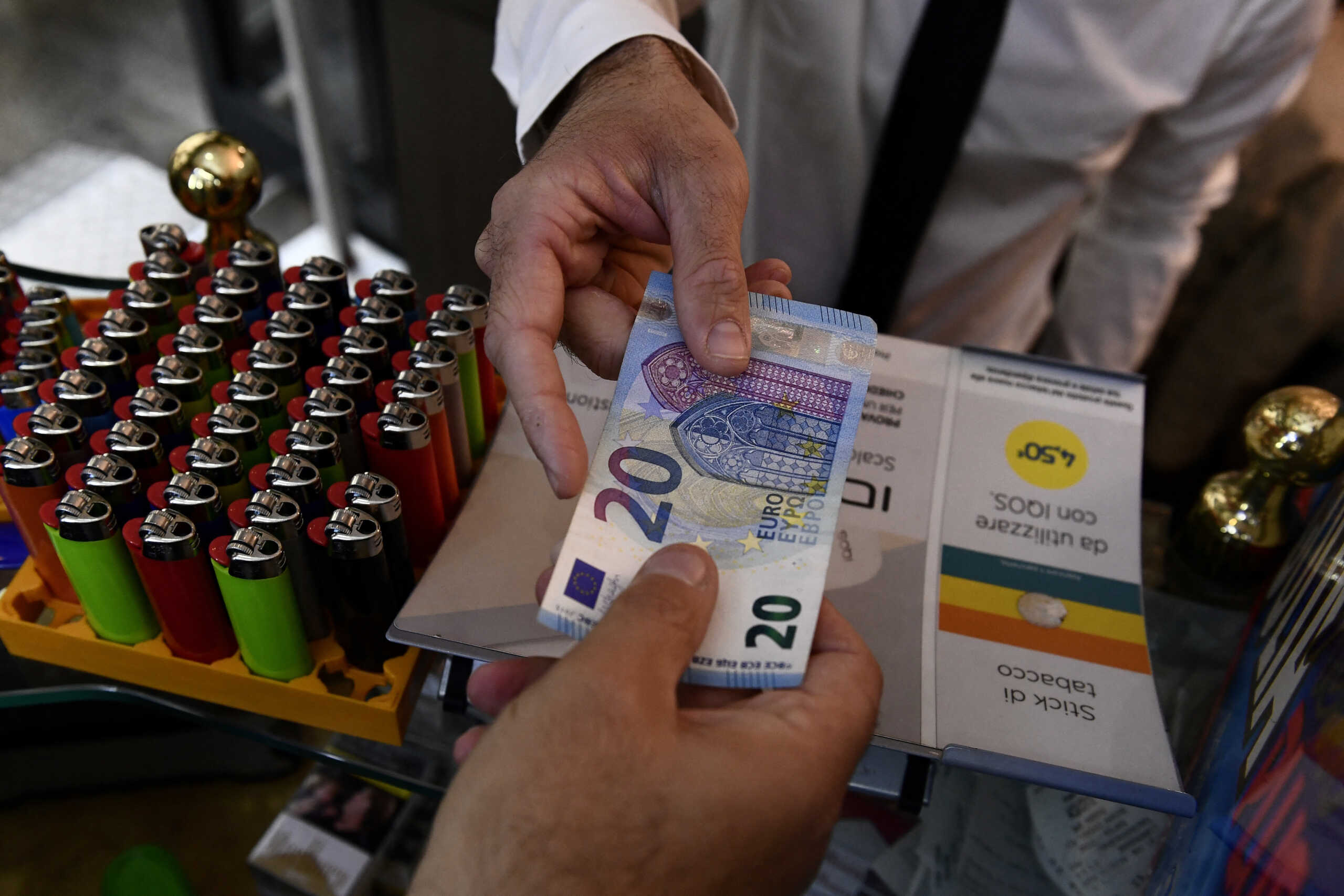 FILE PHOTO: A man uses cash to pay for items while shopping in Milan, Italy, October 2, 2020. Picture taken October 2, 2020. REUTERS