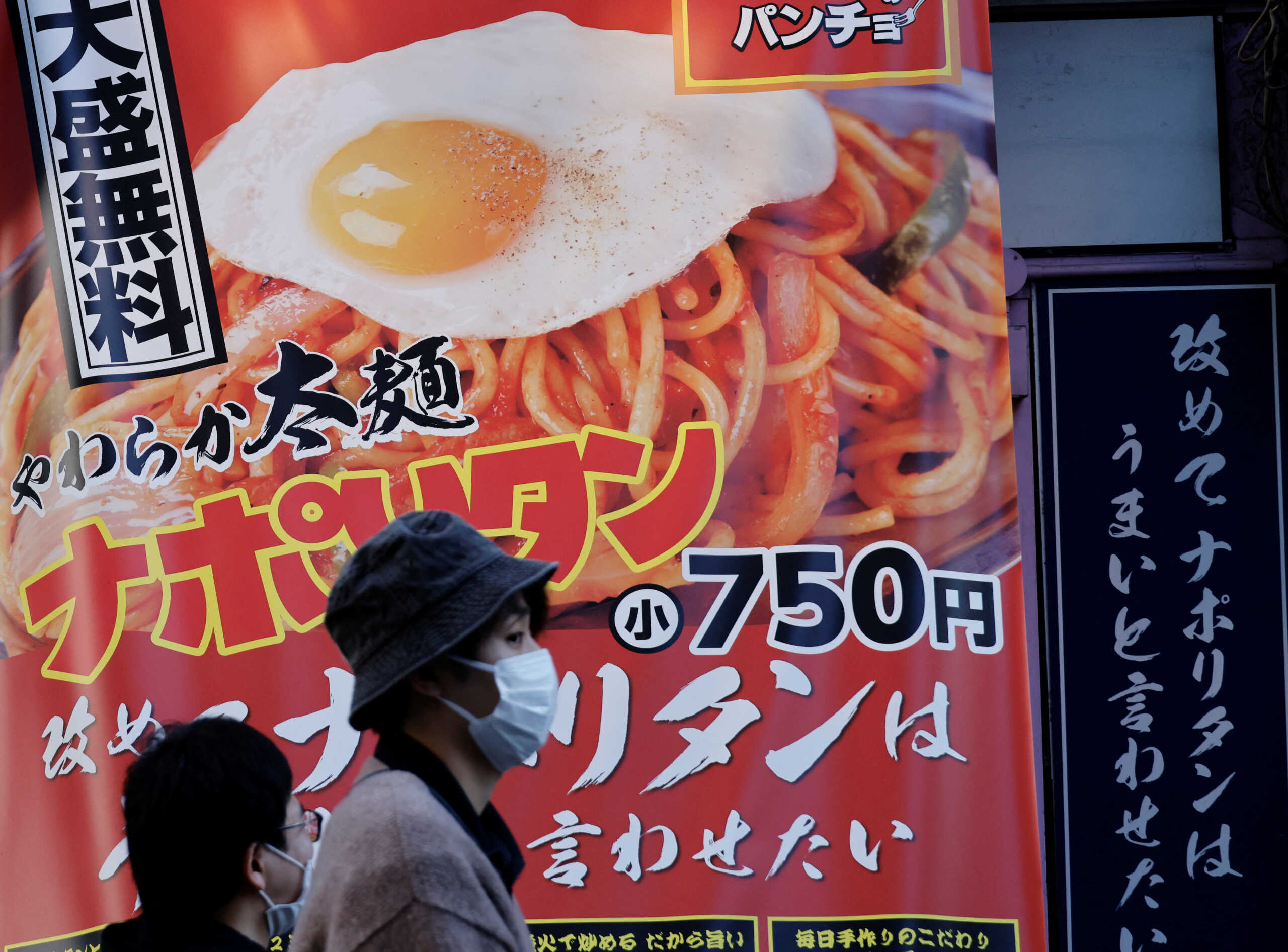 People walk past a signboard of a restaurant at a shopping district in Tokyo, Japan October 28, 2022. REUTERS