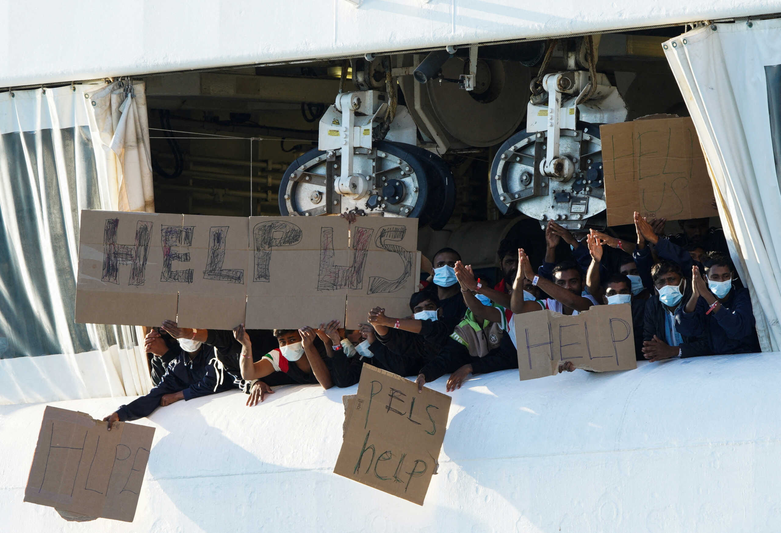 Migrants remaining on the rescue ship Geo Barents hold banners after Italy allowed the disembarkation of children and sick people, in the port of Catania, Italy, November 7, 2022. REUTERS