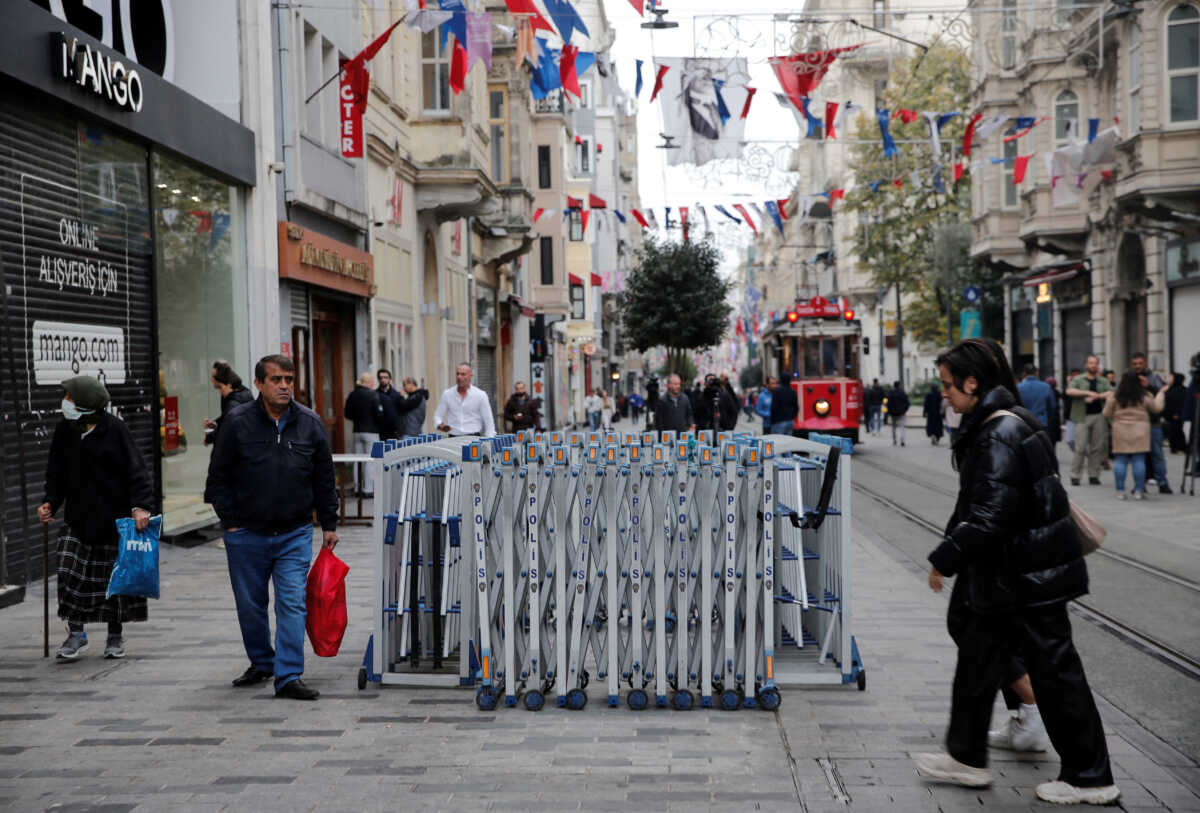 People walk along Istiklal Avenue, a popular spot for shoppers and tourists, as a blast site is seen behind a police barricade in Istanbul, Turkey, November 14, 2022. REUTERS