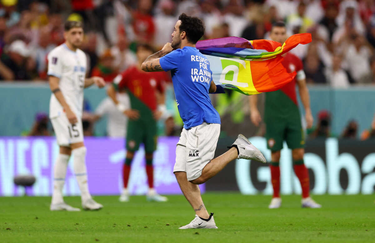 Soccer Football - FIFA World Cup Qatar 2022 - Group H - Portugal v Uruguay - Lusail Stadium, Lusail, Qatar - November 28, 2022  A pitch invader runs onto the pitch wearing a t-shirt with a message saying 'Respect for Iranian Women' and holding a rainbow flag REUTERS