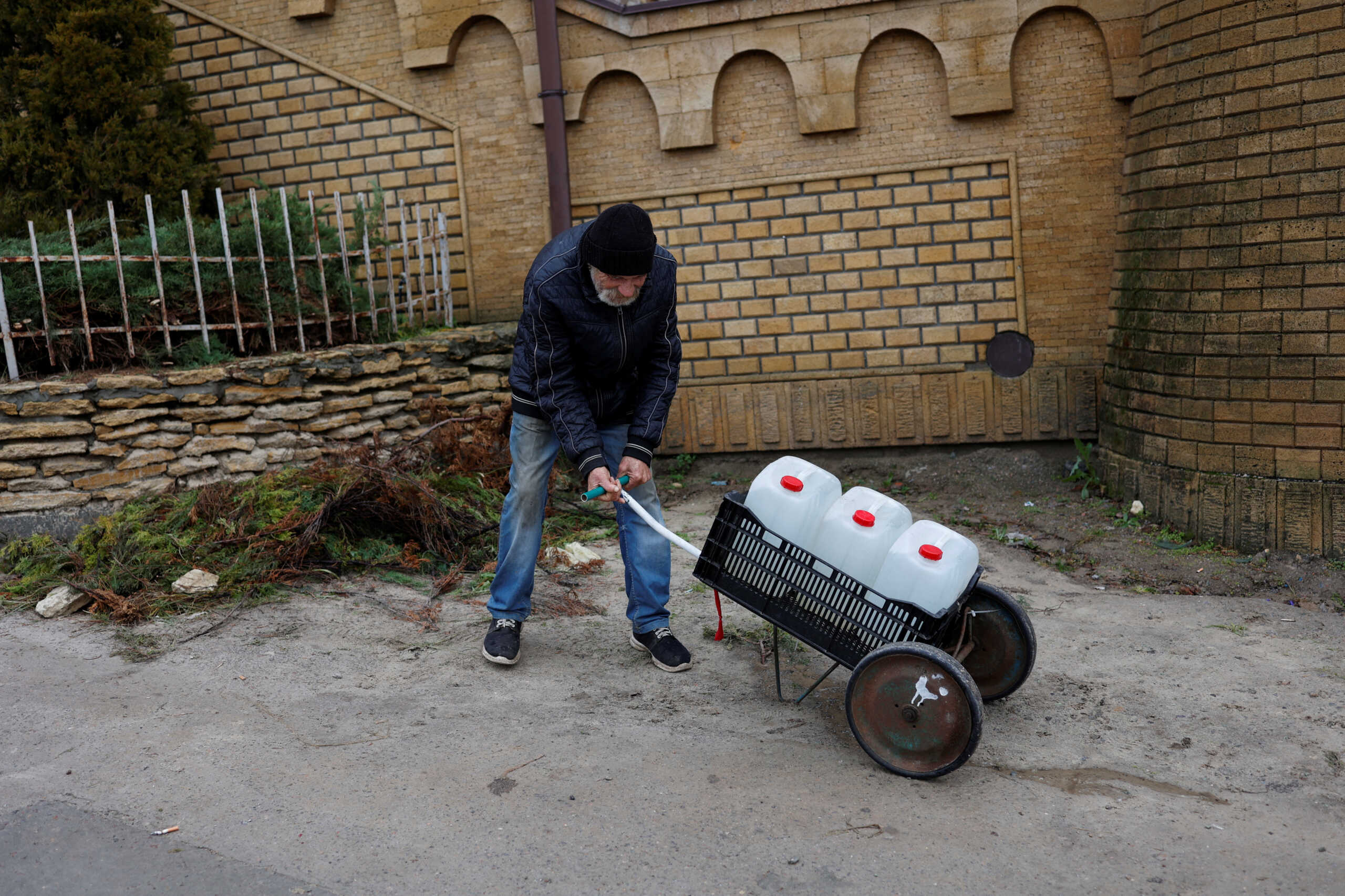A man tries to carry water containers near Dnipro river after Russia's military retreat from Kherson, Ukraine November 21, 2022. REUTERS