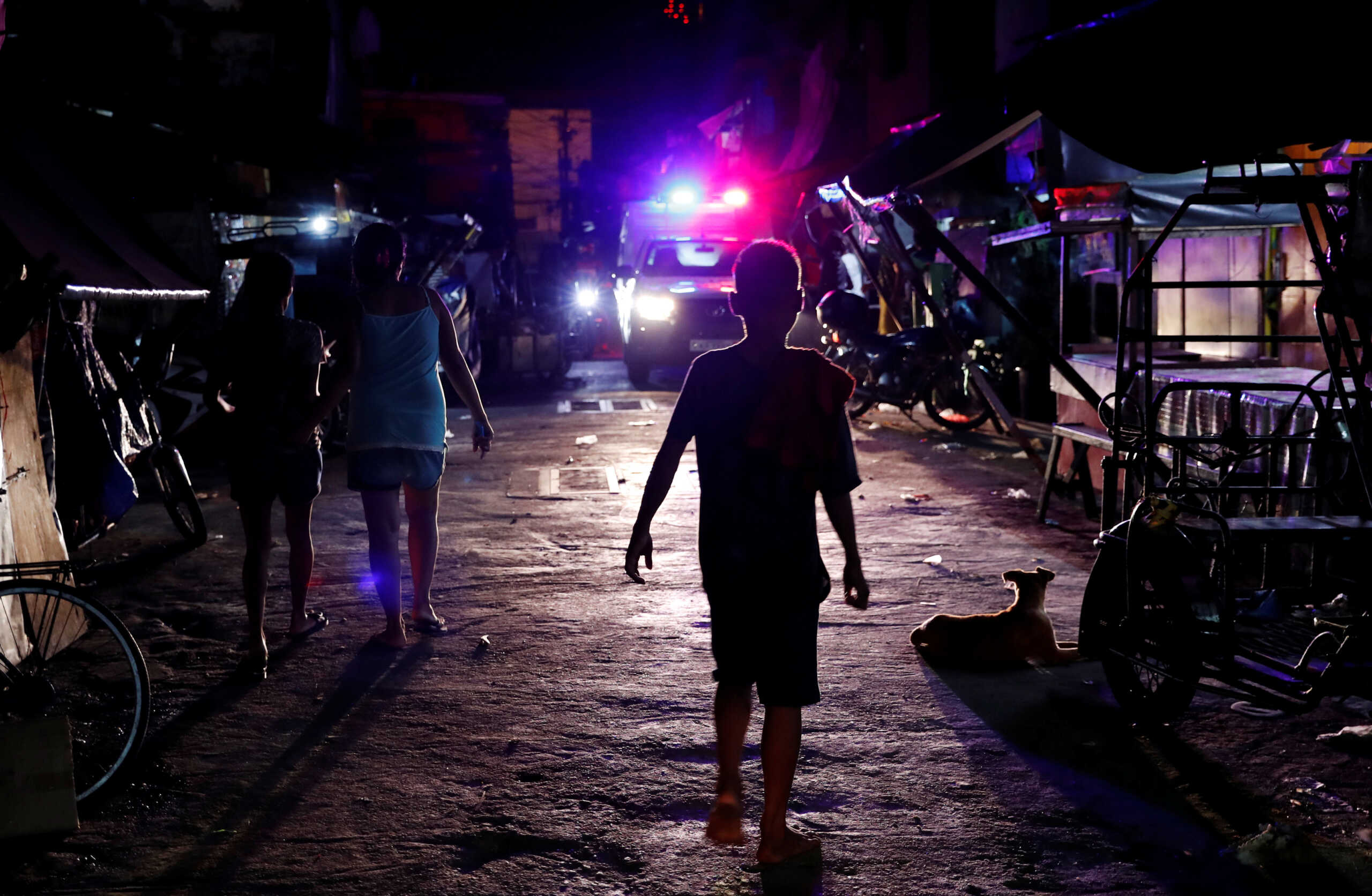 Residents walk along a street as a police vehicle patrols the streets of Tondo, Manila, Philippines July 2, 2018. Picture taken July 2, 2018. REUTERS