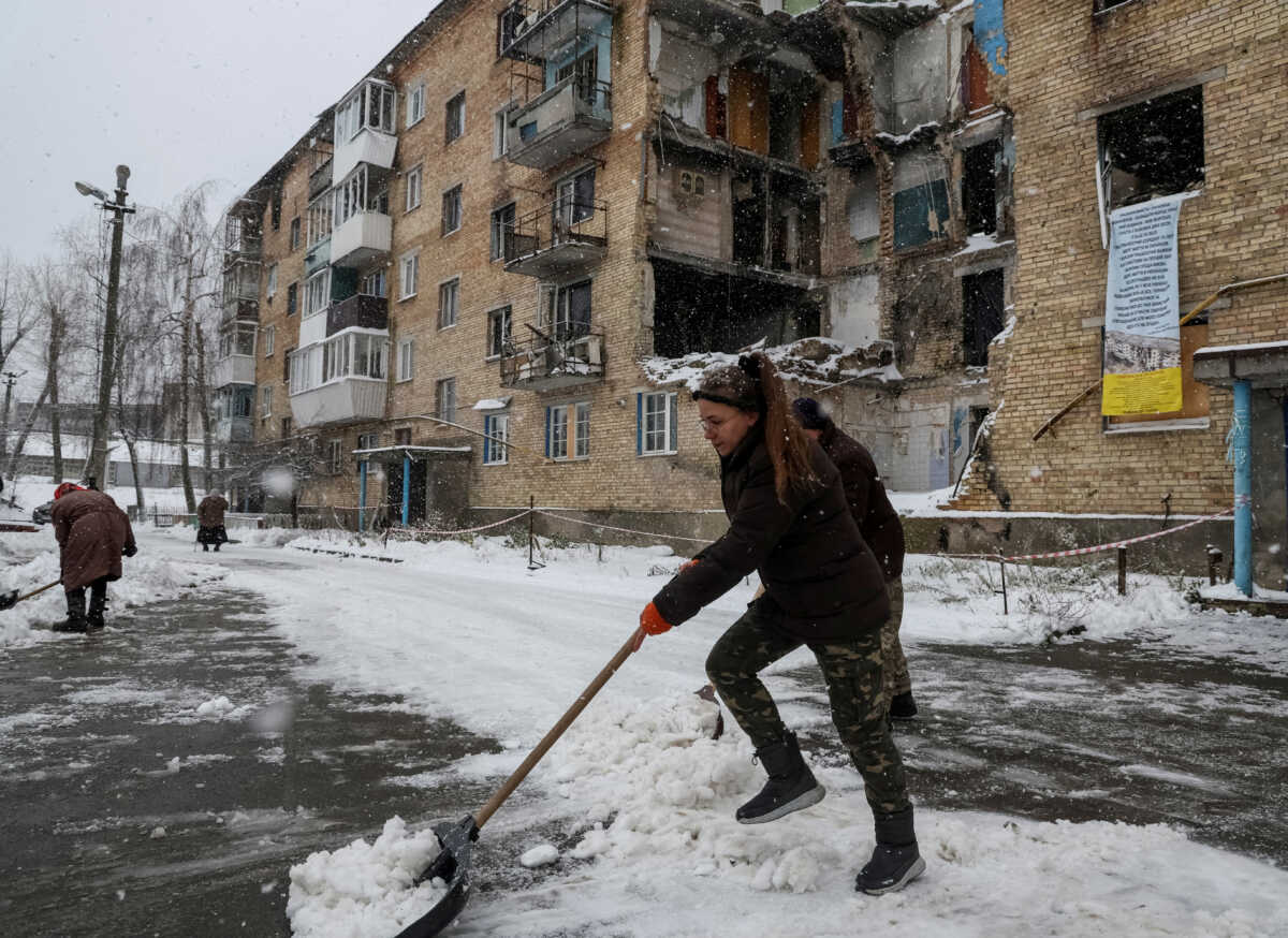 FILE PHOTO: Tetiana Reznychenko, a resident of the Ukrainian village of Horenka, shovels snow near her apartment building, which has no electricity, heating or running water after being heavily damaged in the early days of the Russian invasion, November 19, 2022. REUTERS