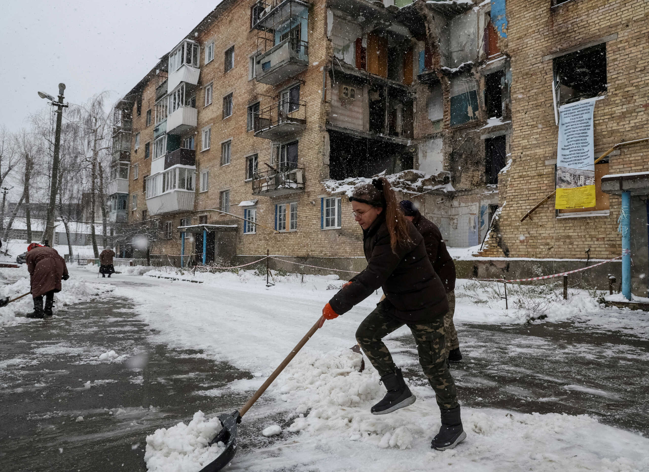 FILE PHOTO: Tetiana Reznychenko, a resident of the Ukrainian village of Horenka, shovels snow near her apartment building, which has no electricity, heating or running water after being heavily damaged in the early days of the Russian invasion, November 19, 2022. REUTERS