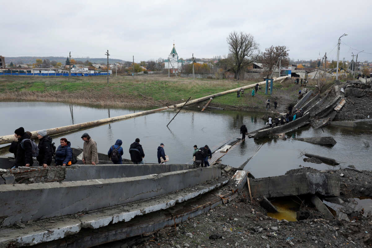 People leave and return to their shelters as they cross a destroyed bridge in order to collect aid, as Russia's invasion of Ukraine continues, in the eastern Donbas region of Bakhmut, Ukraine, October 30, 2022. REUTERS