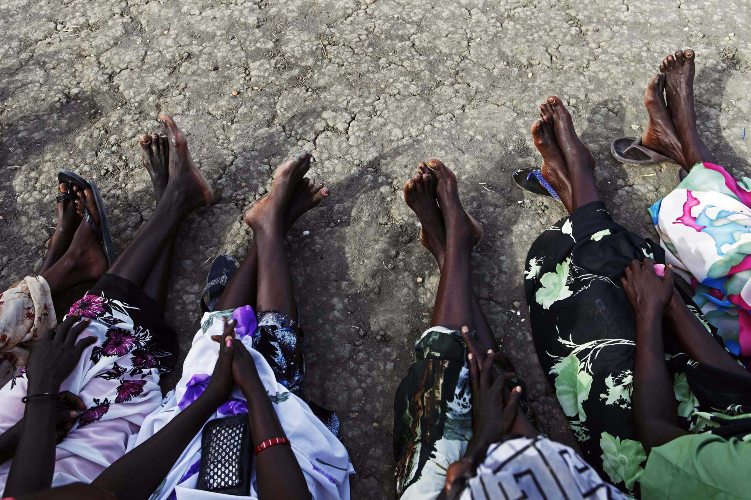 Sudanese women sit barefoot while waiting in line outside a polling station in the town of Malakal in Upper Nile state April 13, 2010. REUTERS