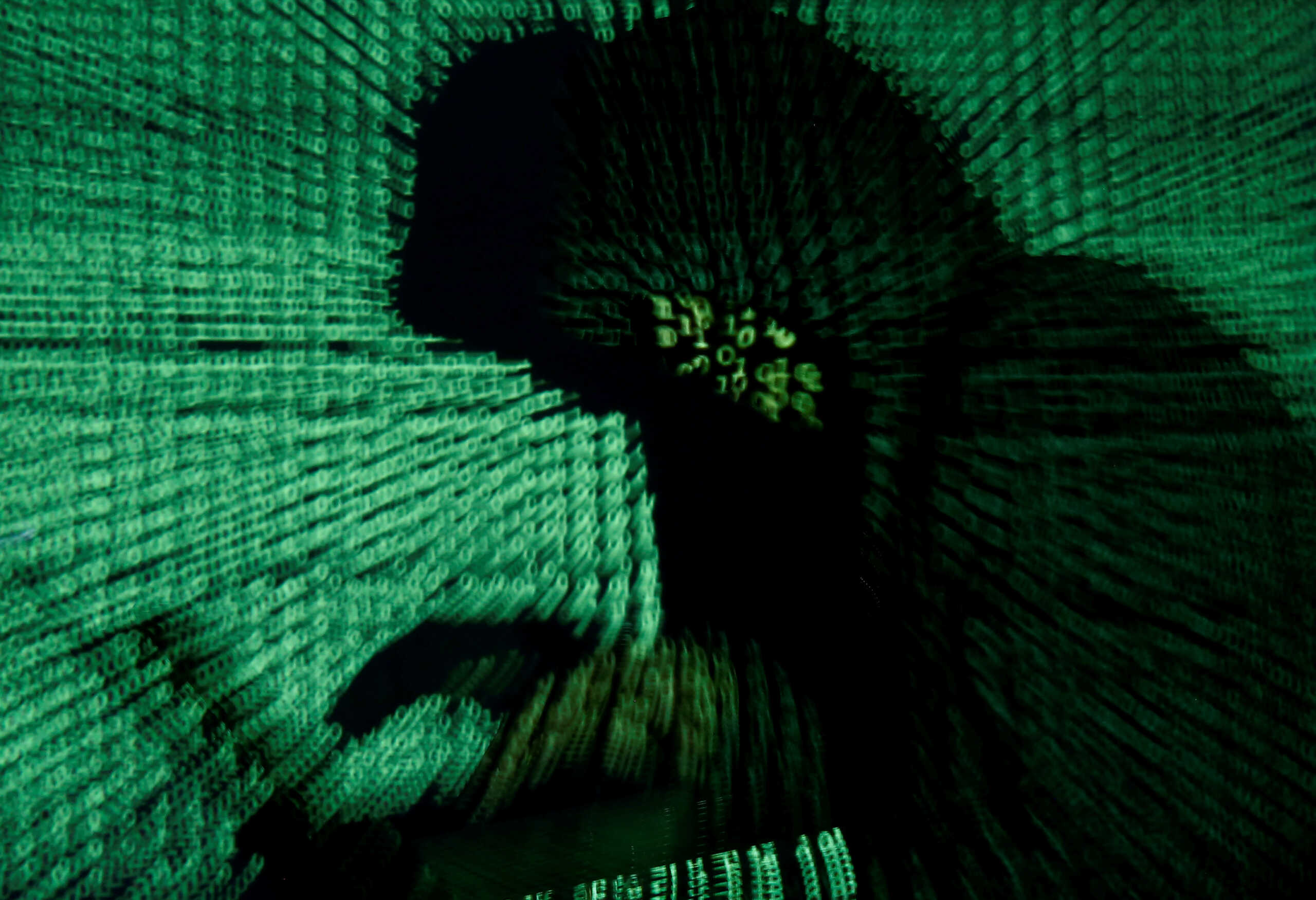 FILE PHOTO: A man holds a laptop computer as cyber code is projected on him in this illustration picture taken on May 13, 2017. REUTERS