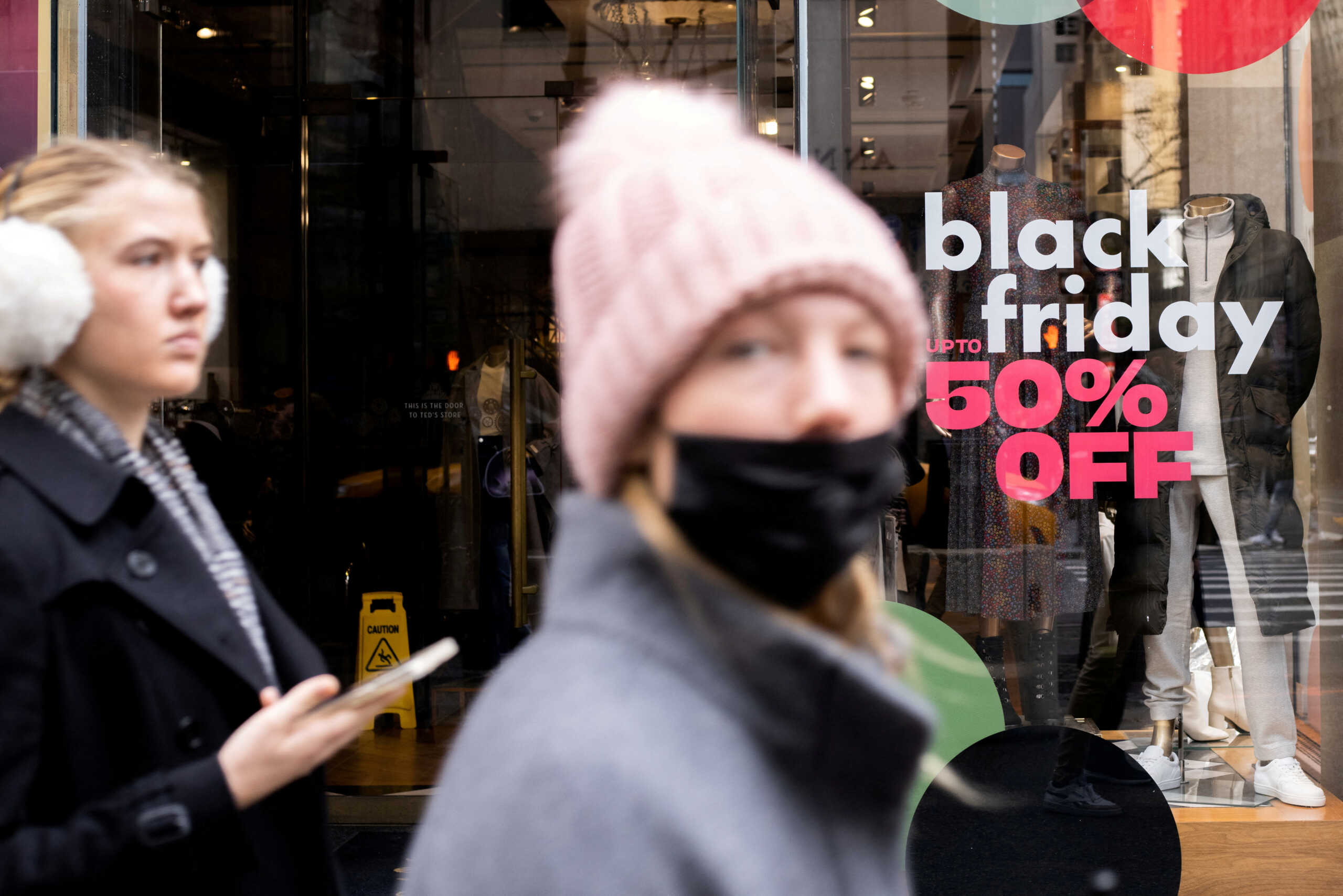 FILE PHOTO: People walk along a store with sales signage during Black Friday sales in the Manhattan borough of New York City, New York, U.S., November 26, 2021. REUTERS