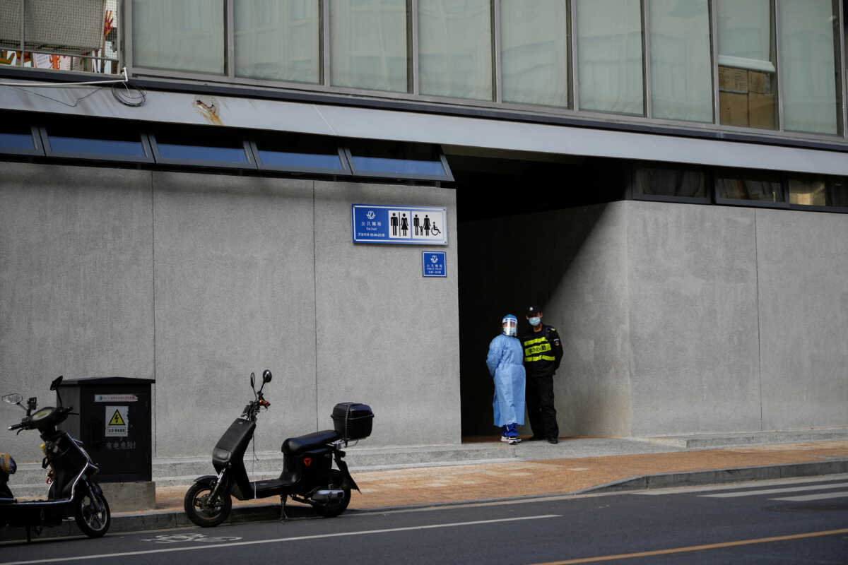 A worker in protective suit keeps a watch outside a public toilet to inspect the health code of visitors, amid the coronavirus disease (COVID-19) outbreak in Shanghai, China, November 21, 2022. REUTERS