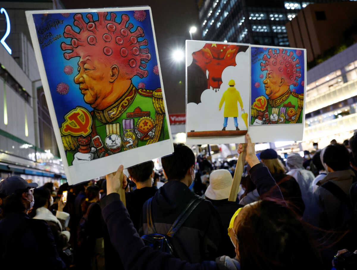 A woman from Hong Kong holds a placard depicting Chinese President Xi Jinping, during in a solidarity protest against China's COVID-19 lockdowns, in Tokyo, Japan, November 30, 2022. REUTERS