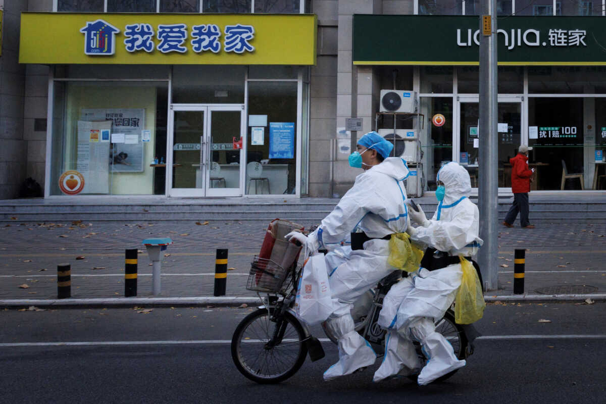 Pandemic prevention workers in protective suits ride an electric bike as outbreaks of coronavirus disease (COVID-19) continue in Beijing, November 21, 2022. REUTERS