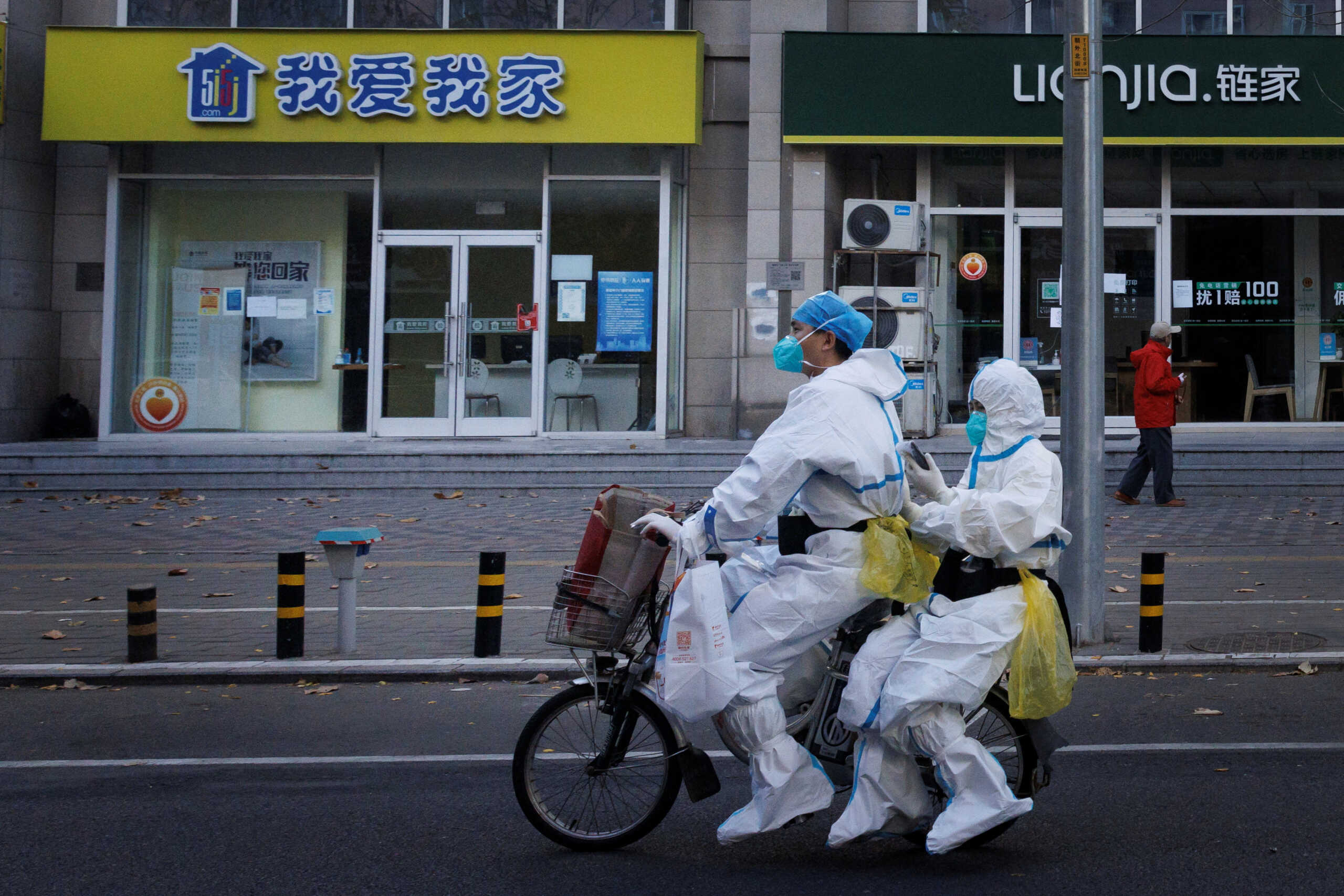 Pandemic prevention workers in protective suits ride an electric bike as outbreaks of coronavirus disease (COVID-19) continue in Beijing, November 21, 2022. REUTERS