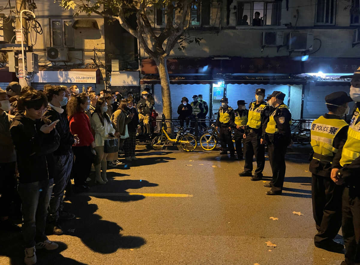 People stand in front of a line of police officers during a demonstration against COVID-19 curbs following the deadly Urumqi fire, in Shanghai, China November 27, 2022. REUTERS
