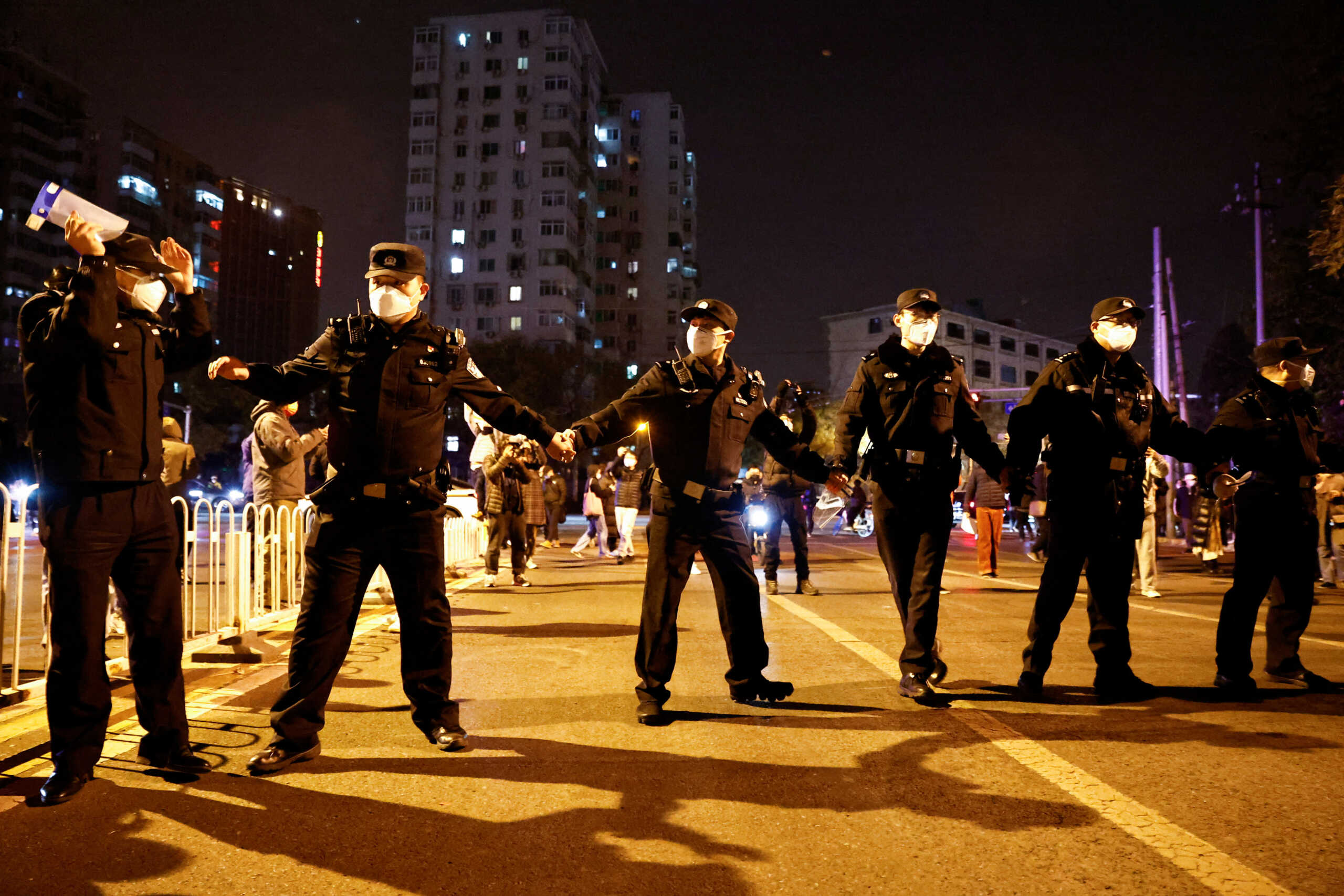 Police officers stand guard as people protest coronavirus disease (COVID-19) restrictions and hold a vigil to commemorate the victims of a fire in Urumqi, as outbreaks of the coronavirus disease continue, in Beijing, China, November 27, 2022. REUTERS