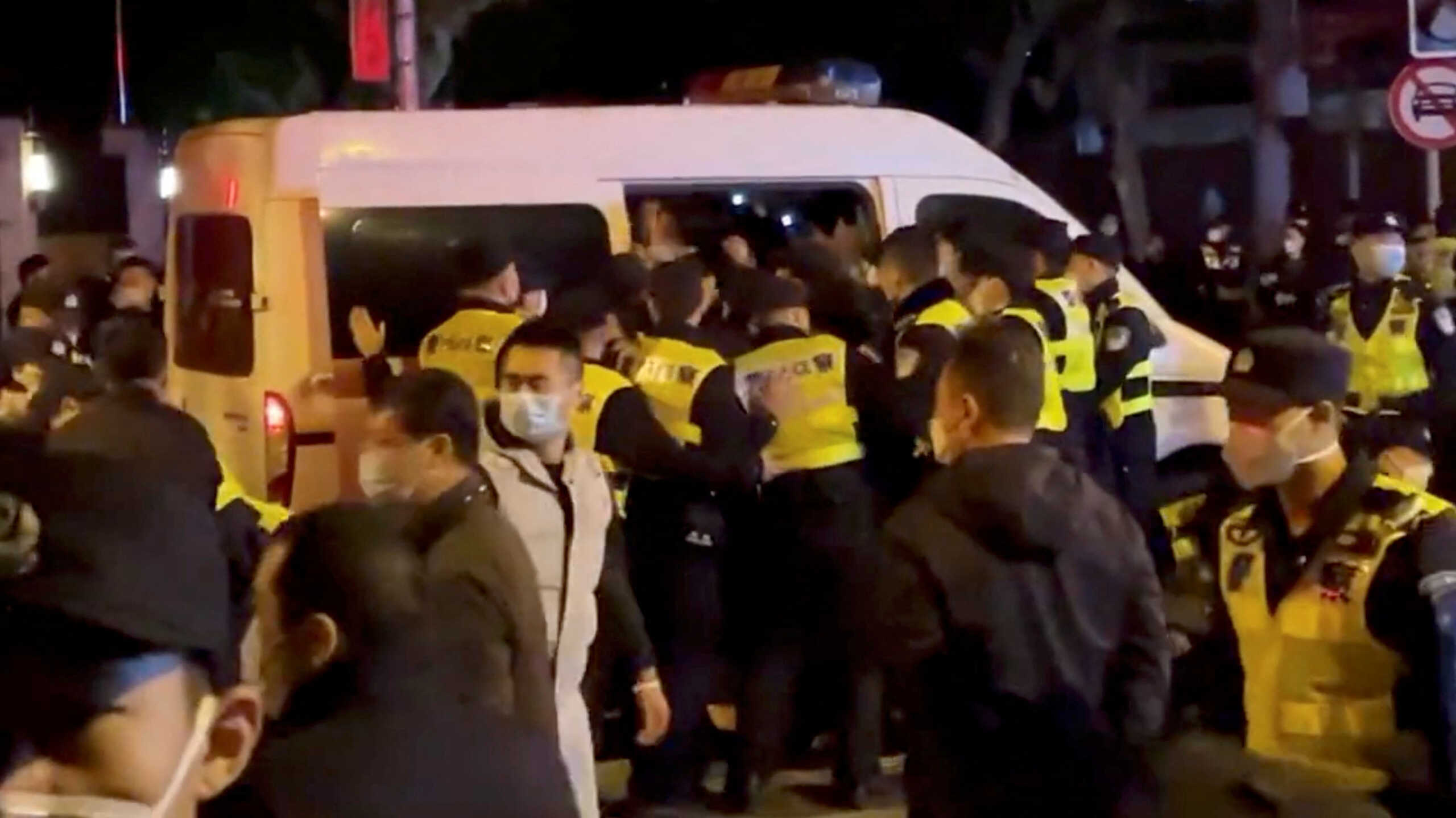 Police officers detain people during a protest against coronavirus disease (COVID-19) curbs at the site of a candlelight vigil for victims of the Urumqi fire, in Shanghai, China in this screengrab obtained from a video released on November 27, 2022. Video obtained by Reuters
