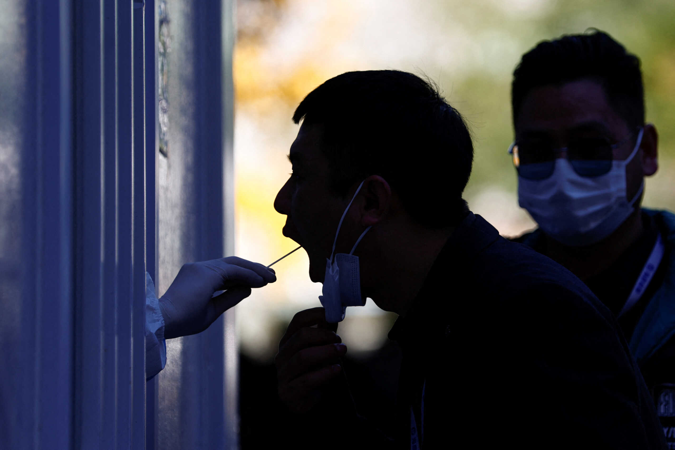 A man has his swab sample taken during nucleic acid test for the coronavirus disease (COVID-19) at a testing booth near an office building in Central Business District (CBD) in Chaoyang district, Beijing, China November 15, 2022. REUTERS