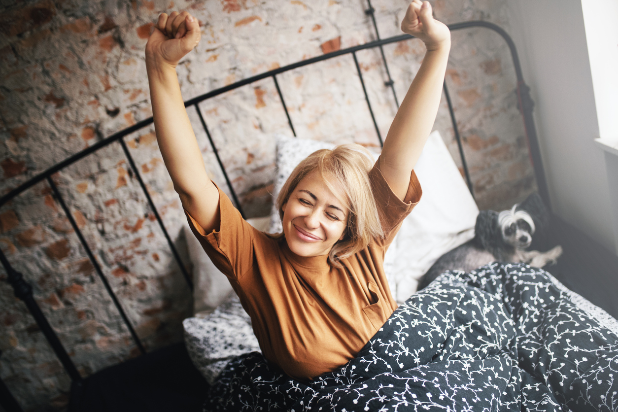 Young woman waking up in the morning. She's satisfied because she had a good night sleep.