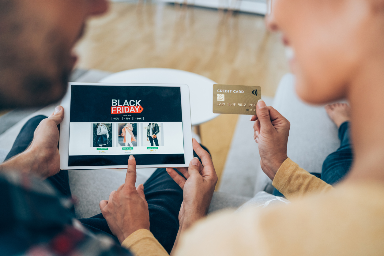 Close-up shot of a young couple holding a digital tablet and shopping online on Black Friday at home.