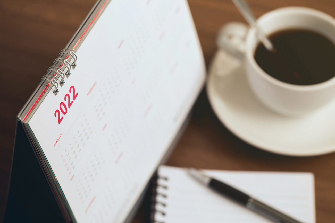 Happy new year 2022 concept.Close up Calendar 2022 schedule with cup of coffee and blank note for to do list on wooden desk.Starting the new year and planning for the future