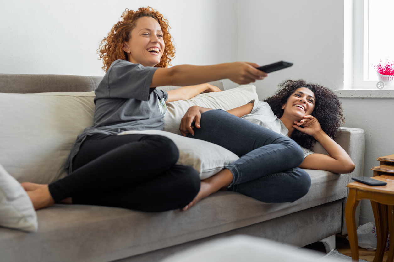 Girlfriends are watching their favorite tv show while sitting on the couch