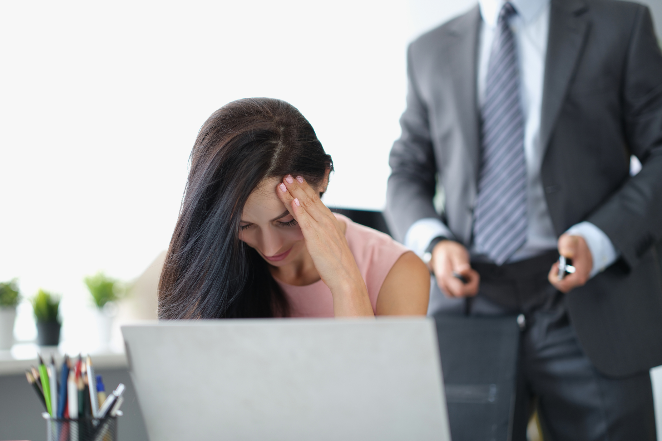 Portrait of secretary close face feeling ashamed and shy because of her boss harassment. Man stand behind with unzip belt on pants. Harassment at workplace
