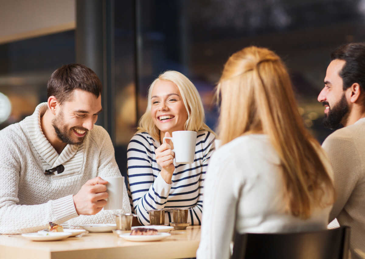 people, leisure and communication concept - happy friends meeting and drinking tea or coffee at cafe