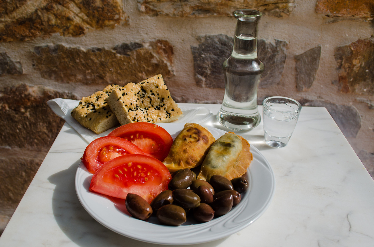 delicious mezes for fasting period and lent including small vegetable pies olives and tomatoes. Ideal for accompanying raki and tsipouro.